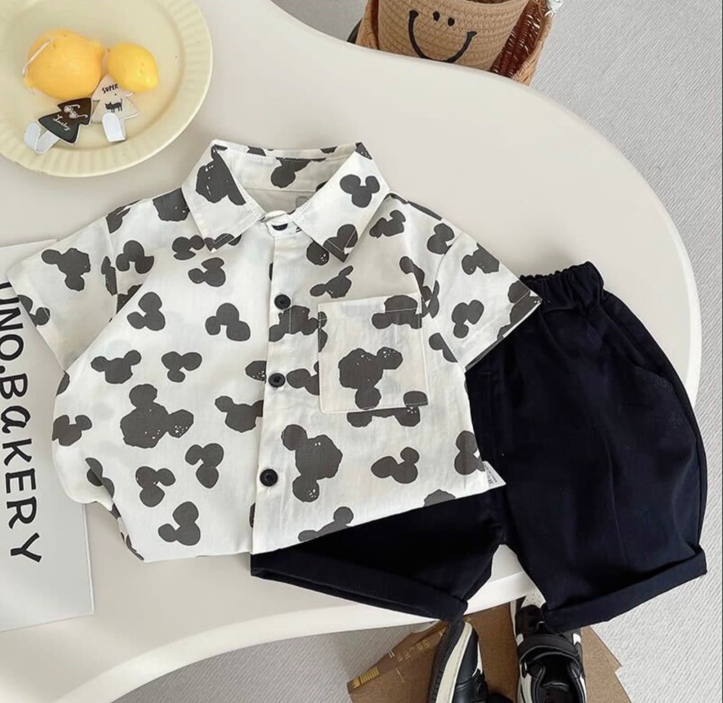 White clothing set with Mickey Mouse print pattern and navy shorts for toddler fashion displayed on light background.