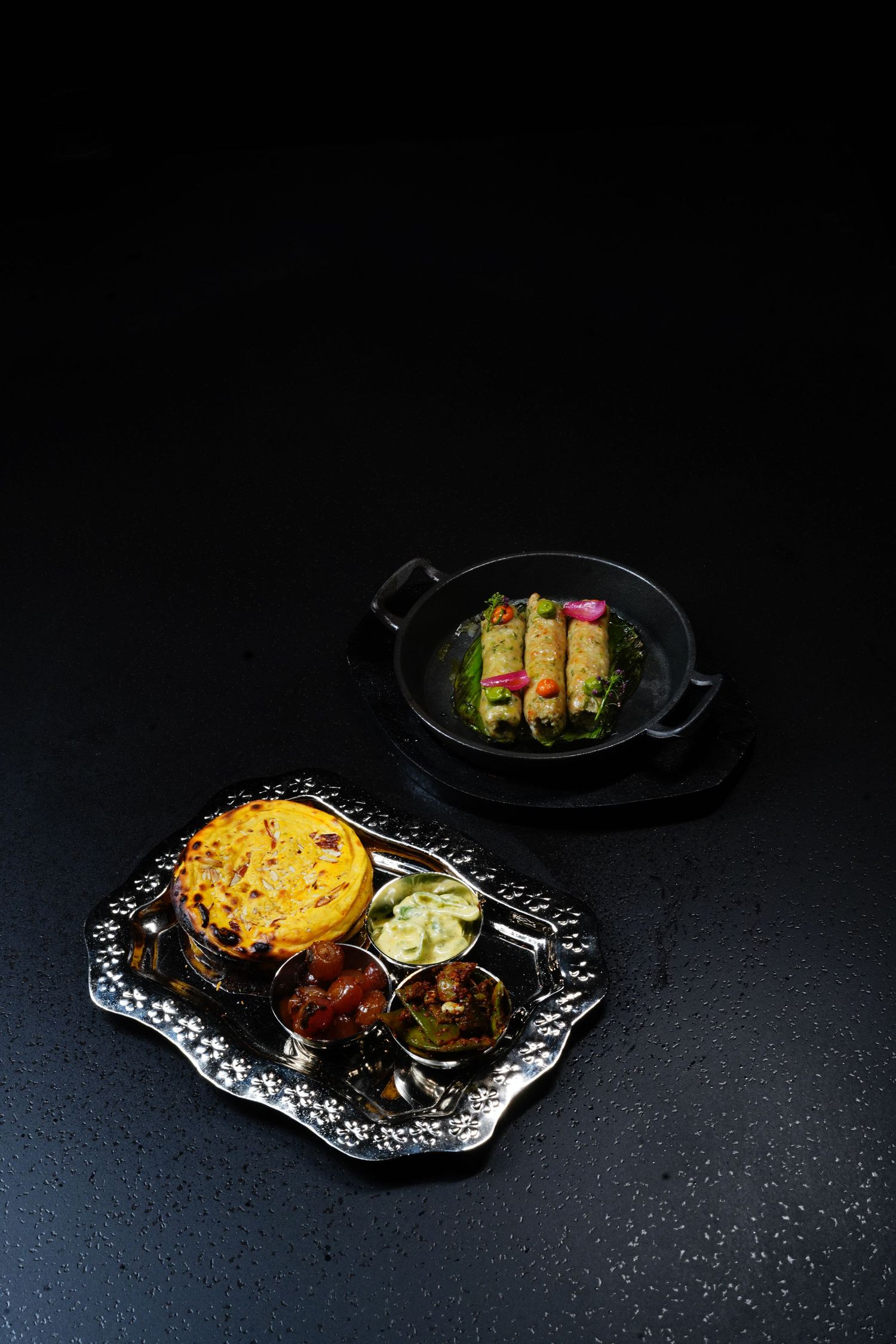 Three elegant dark plates showcase colorful appetizers with garnishes on decorative paper doilies against a black background.
