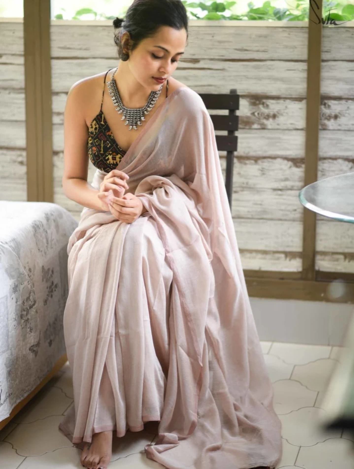 Soft pink silk saree draped elegantly on a white seating arrangement.