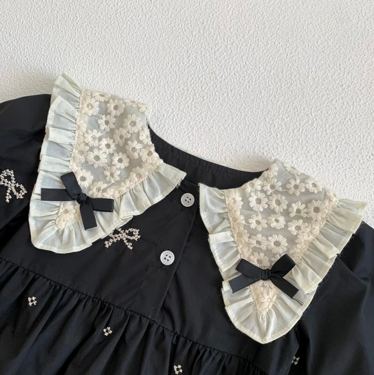 Black and white sheer lace dress features delicate taffeta ruffles and Peter Pan collar details.