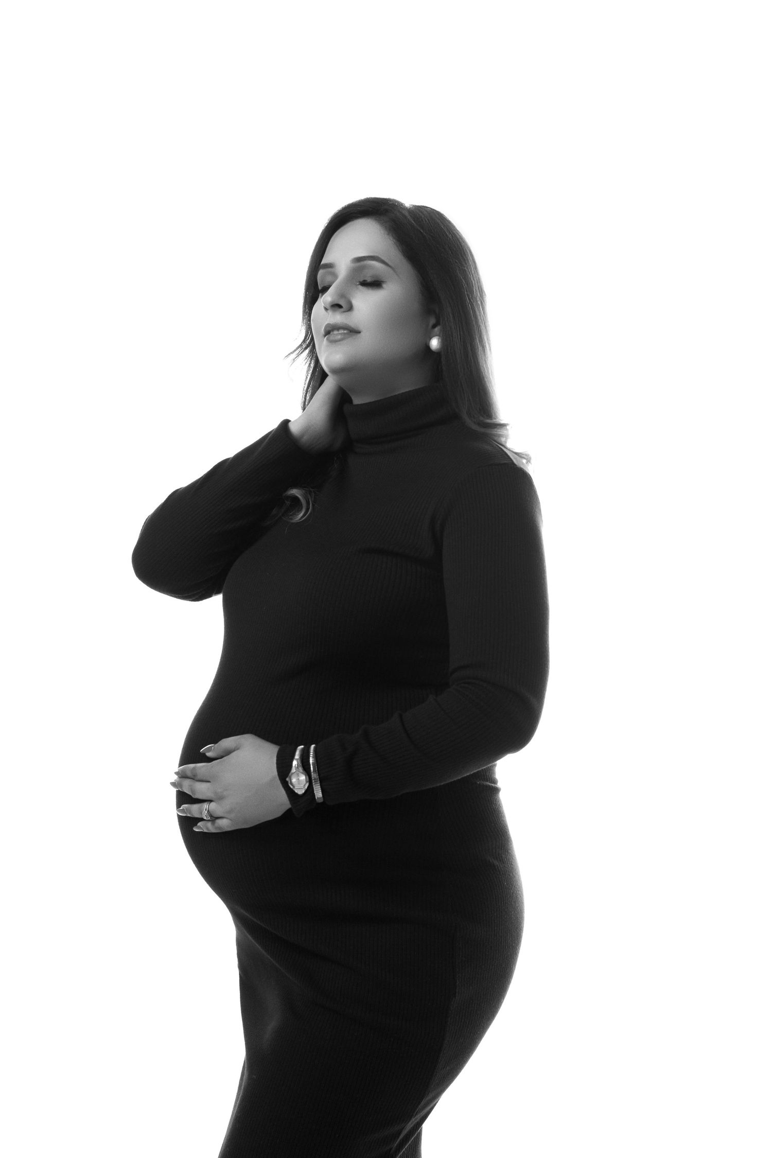Minimalist studio maternity portraits in black dress against white backdrop.