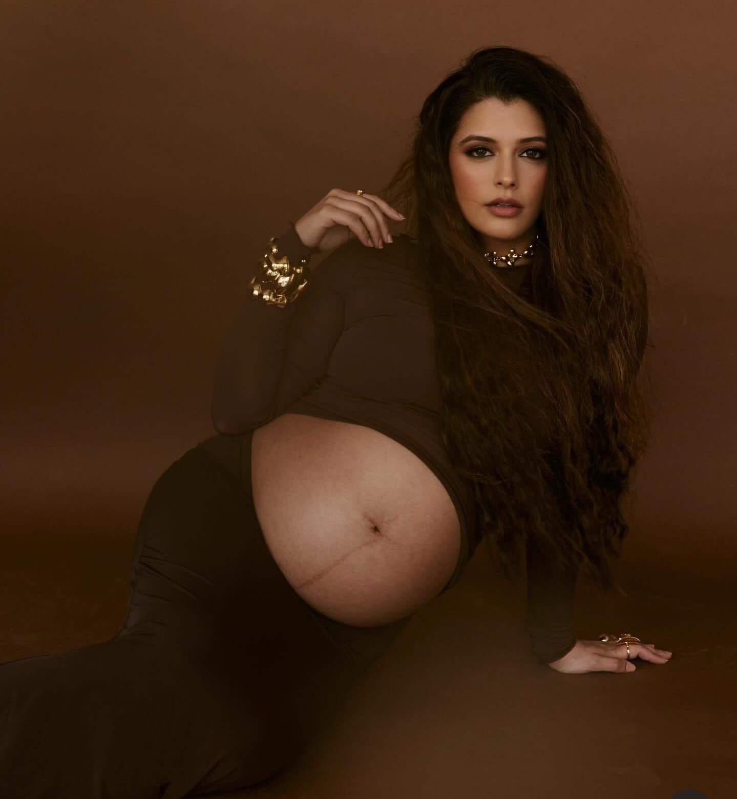 Moody maternity portrait series featuring long dark hair and black clothing against sepia background.
