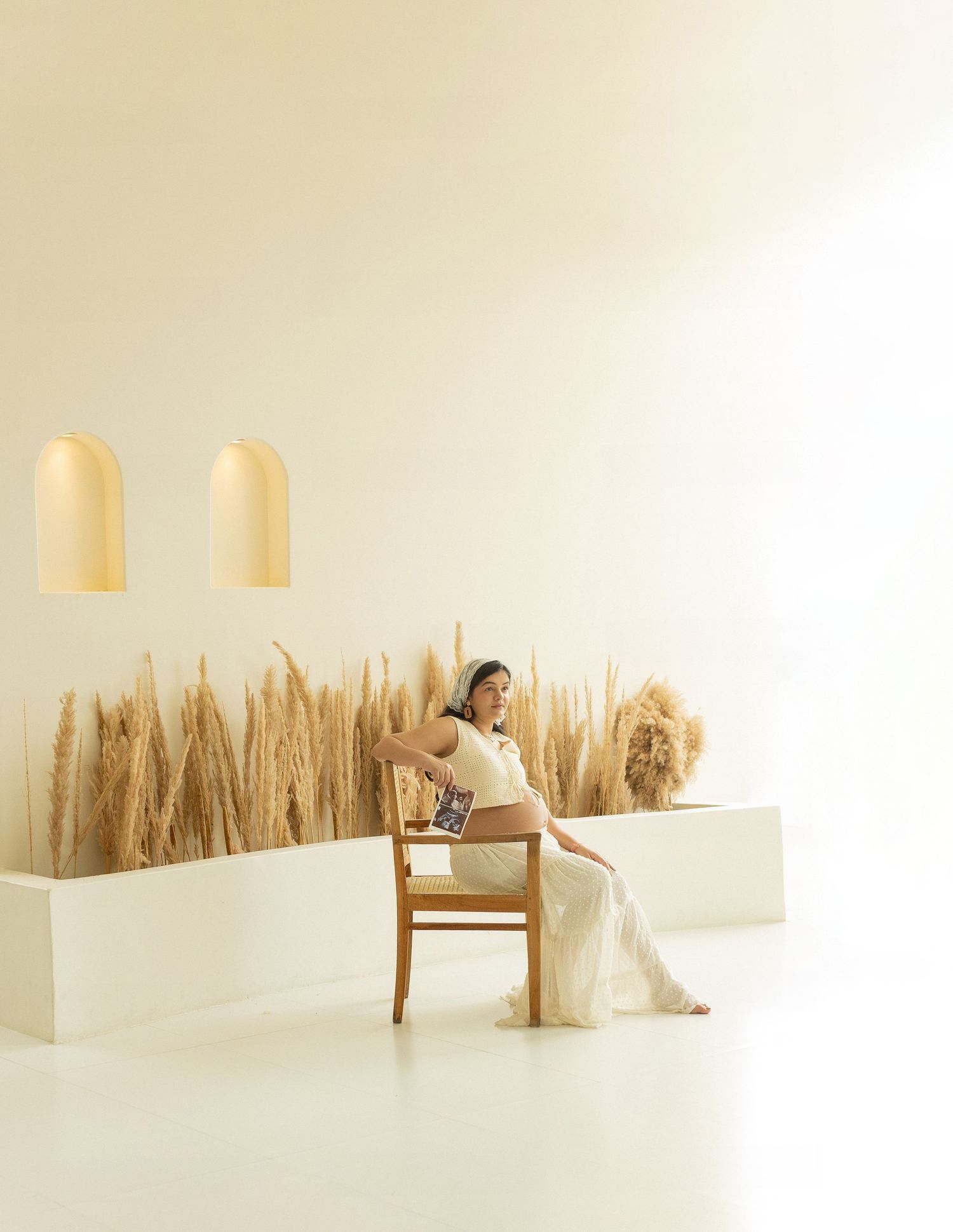 Minimalist interior scene with pampas grass decor, wooden chair, and pendant lights creating a serene atmosphere.