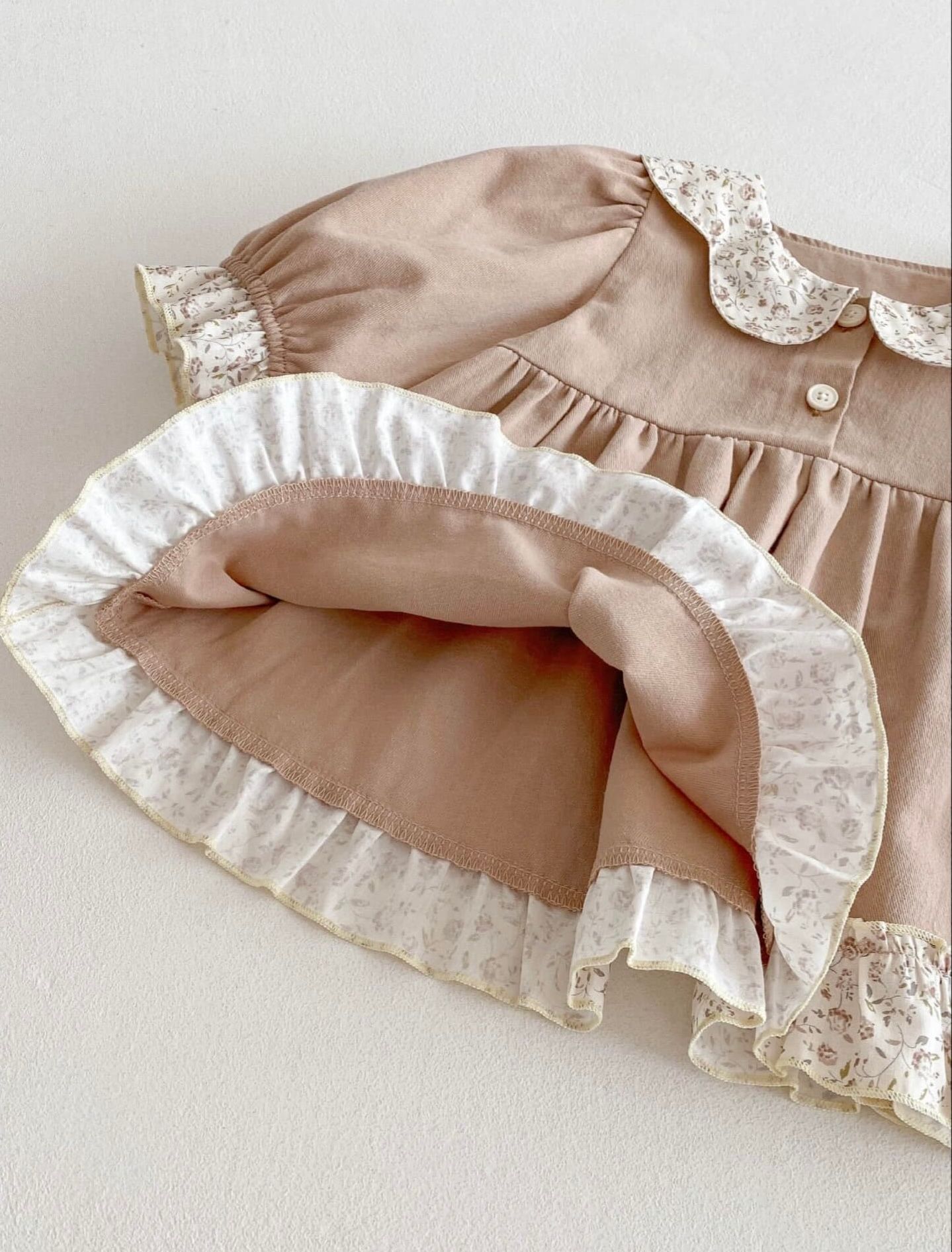 A series of taupe colored fabric ruffles with white lace trim shown in close-up detail.