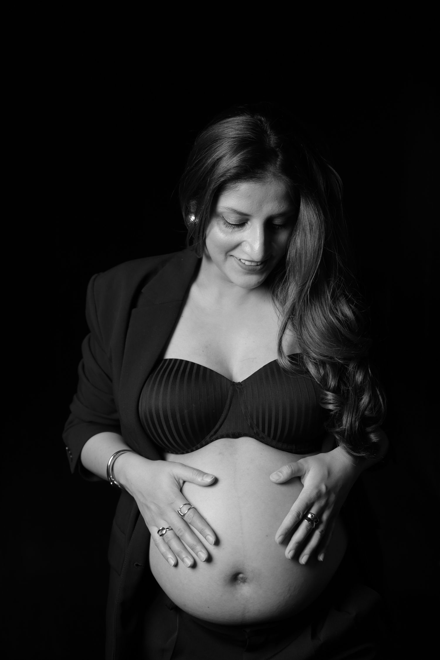 Black and white maternity photo series showing pregnant woman's belly in dramatic lighting.