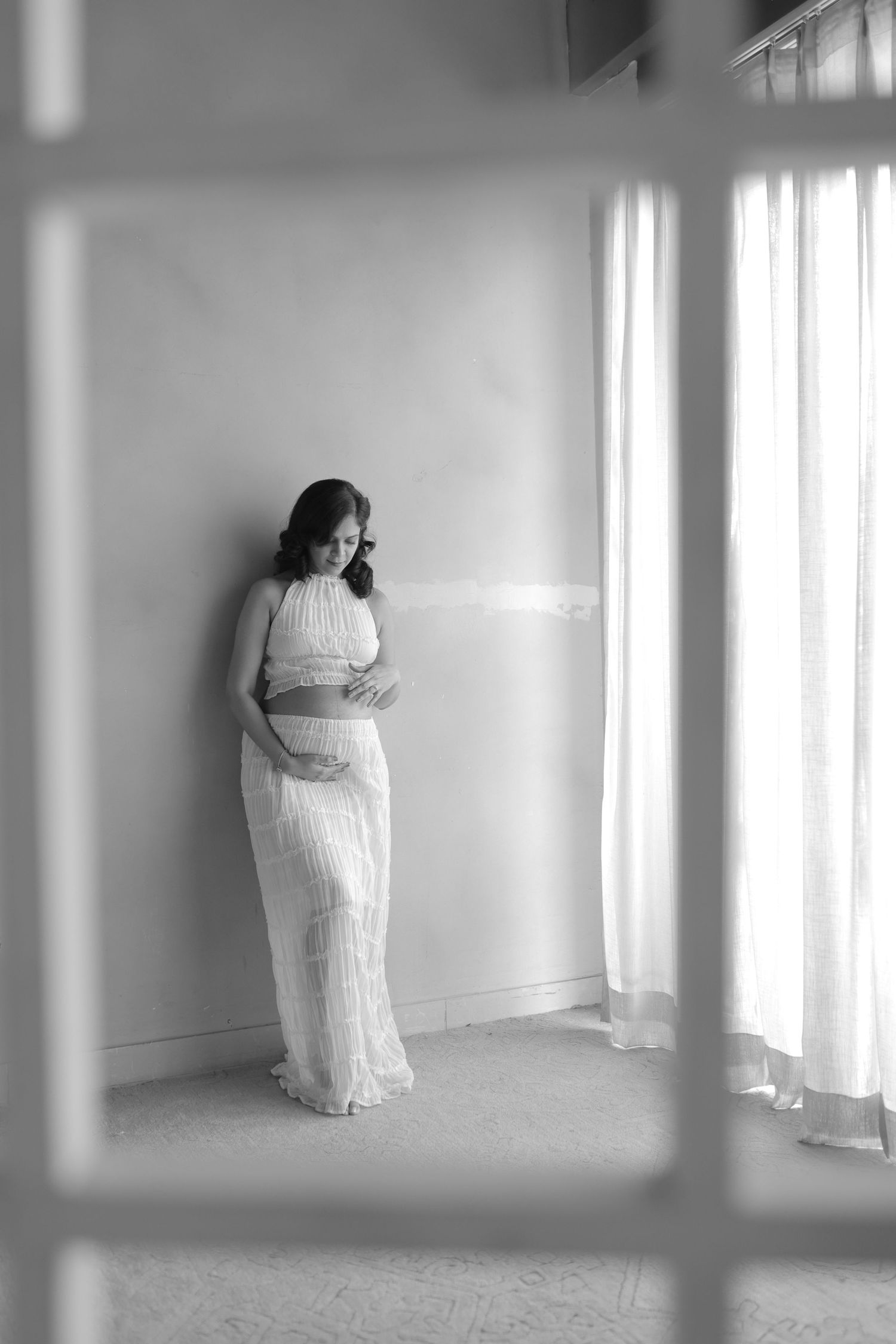 A series of black and white photos showing a person in a white dress standing against a bright minimalist interior.