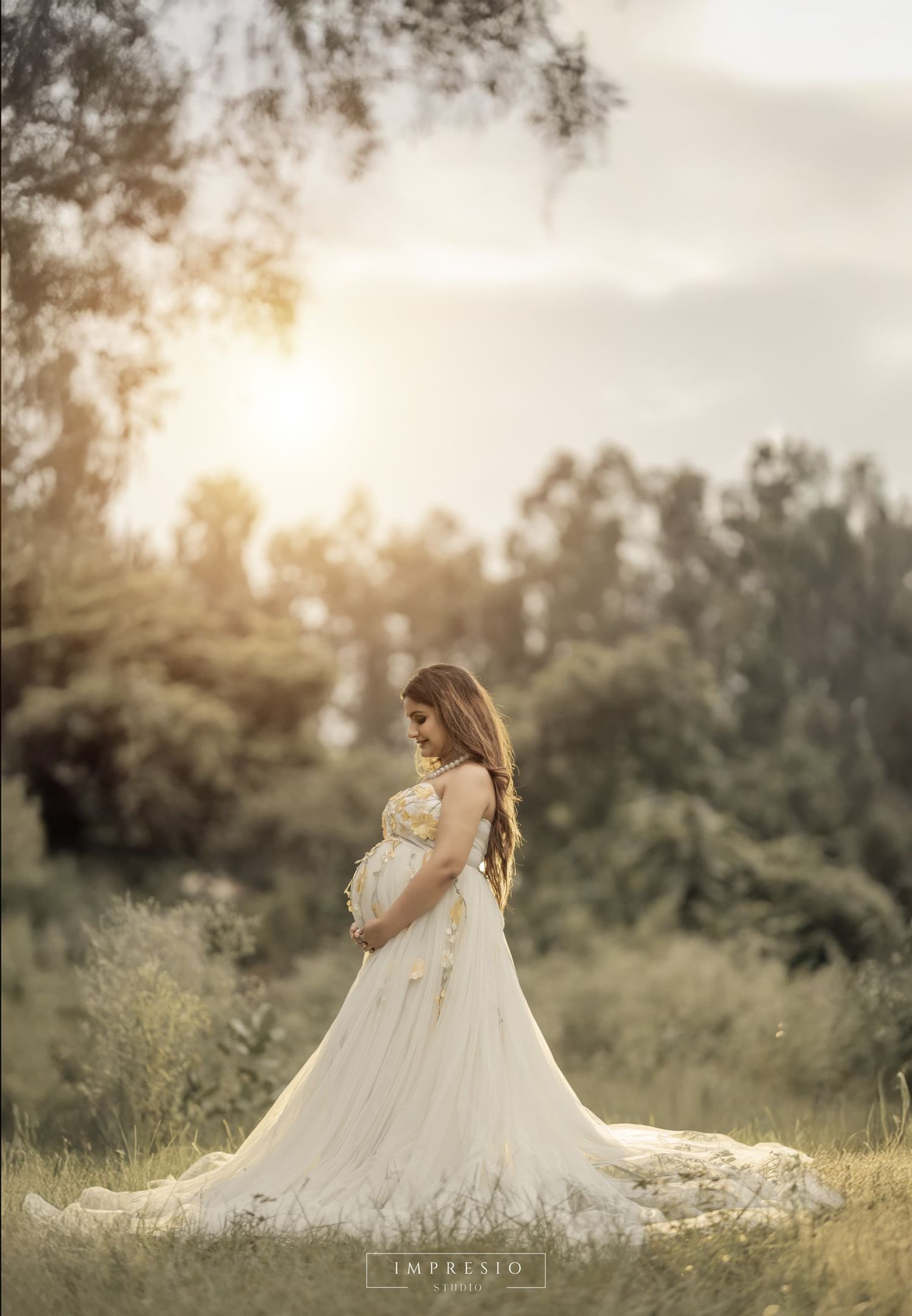Dreamy outdoor maternity photo session at sunset with a flowing white gown.