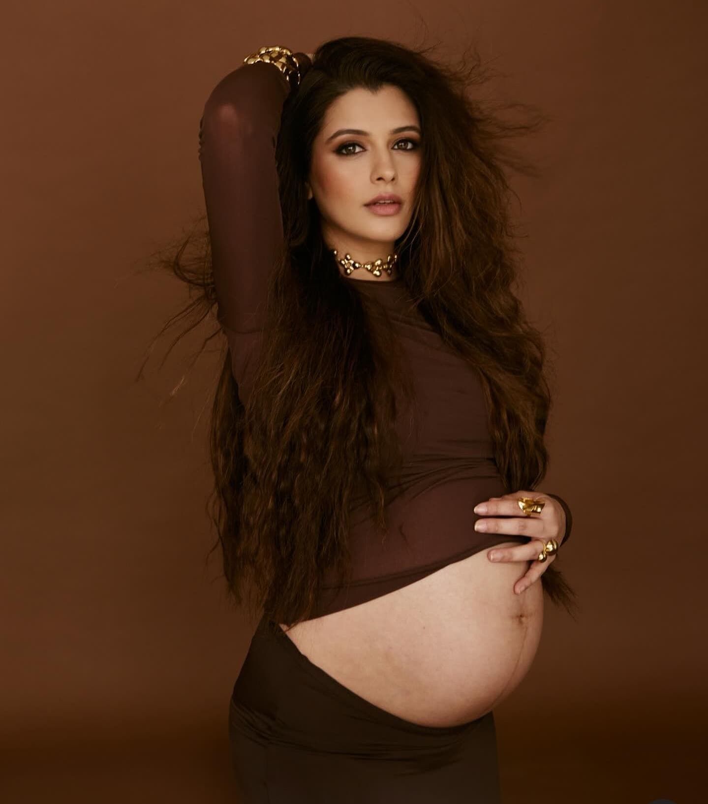 Stylized maternity portrait series with dark brown background and glamorous styling.