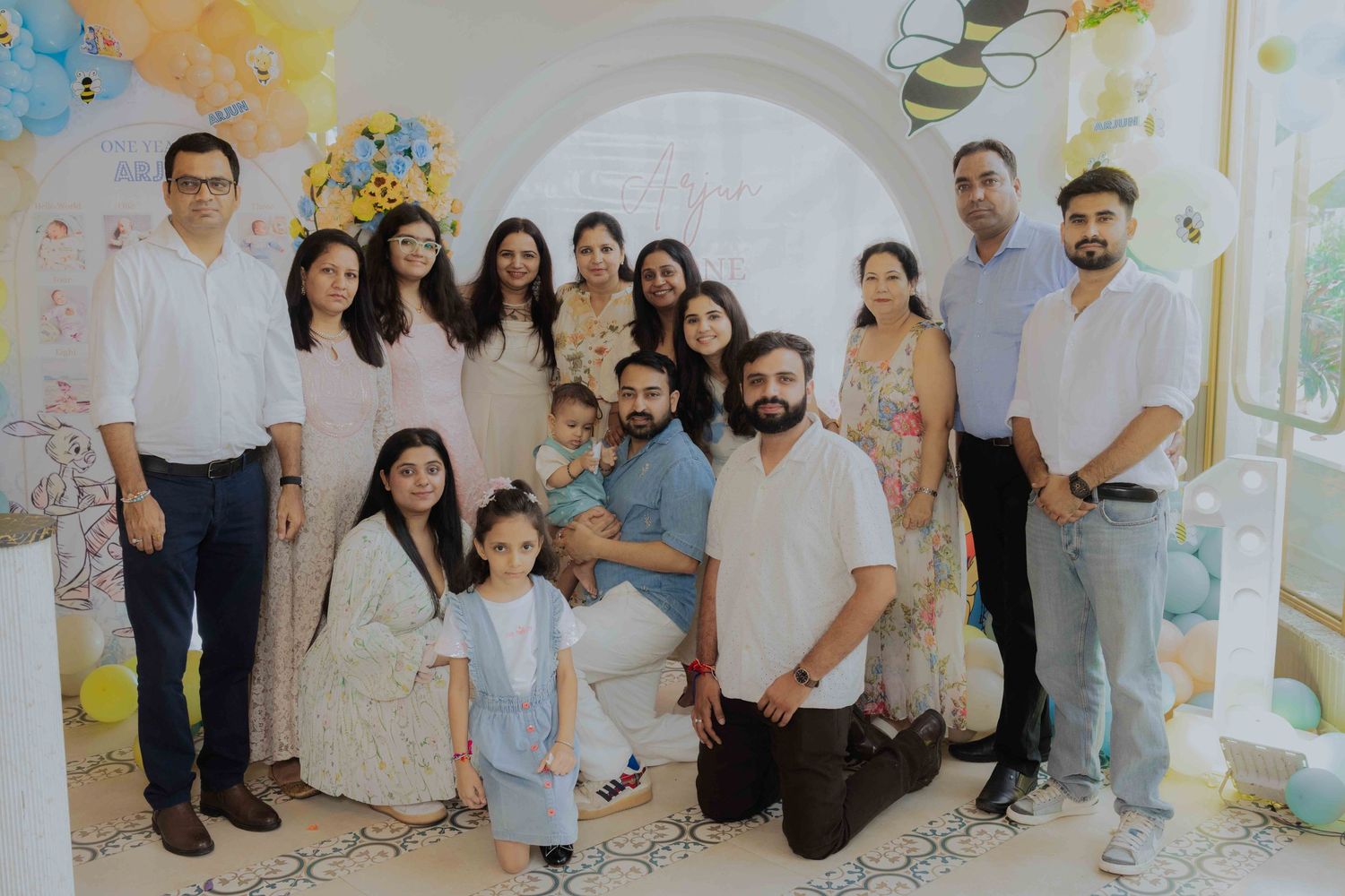 Large family group posing together at a cheerful baby shower decorated with balloons and floral arrangements.