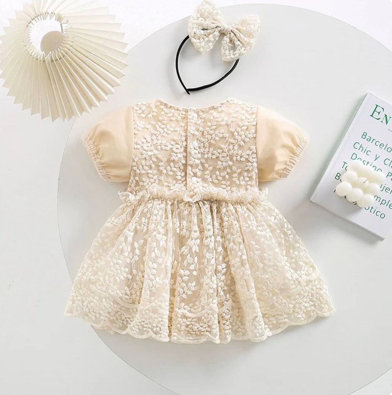 Vintage-style cream lace baby dress with delicate embroidery, ruffled sleeves, and peter pan collar laid flat.
