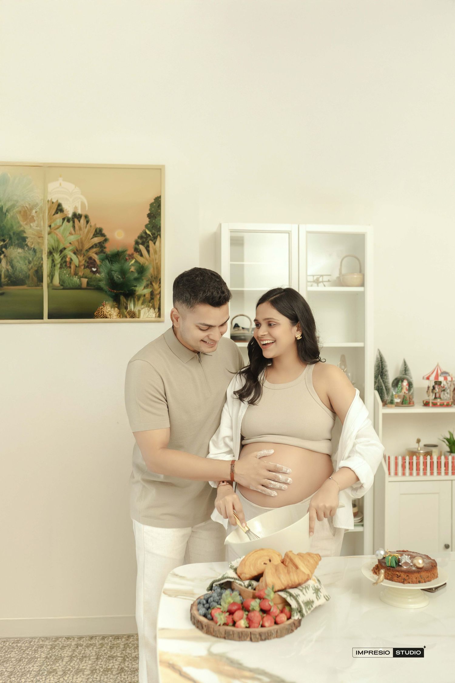 Happy pregnant couple cutting fruit together in a bright, modern kitchen during a maternity photoshoot.