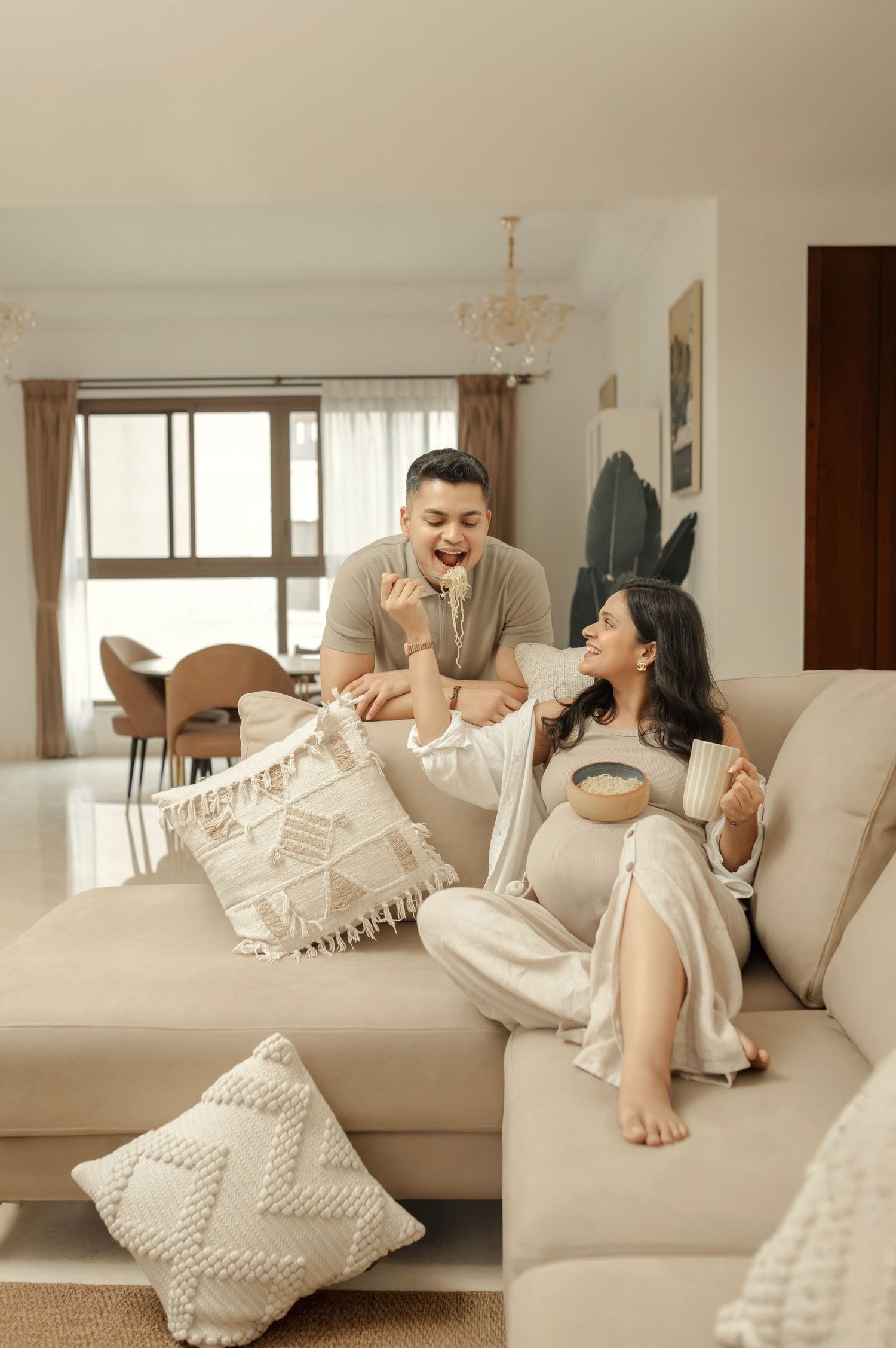 Person lounging comfortably on a white couch in a bright living room wearing a casual white outfit.