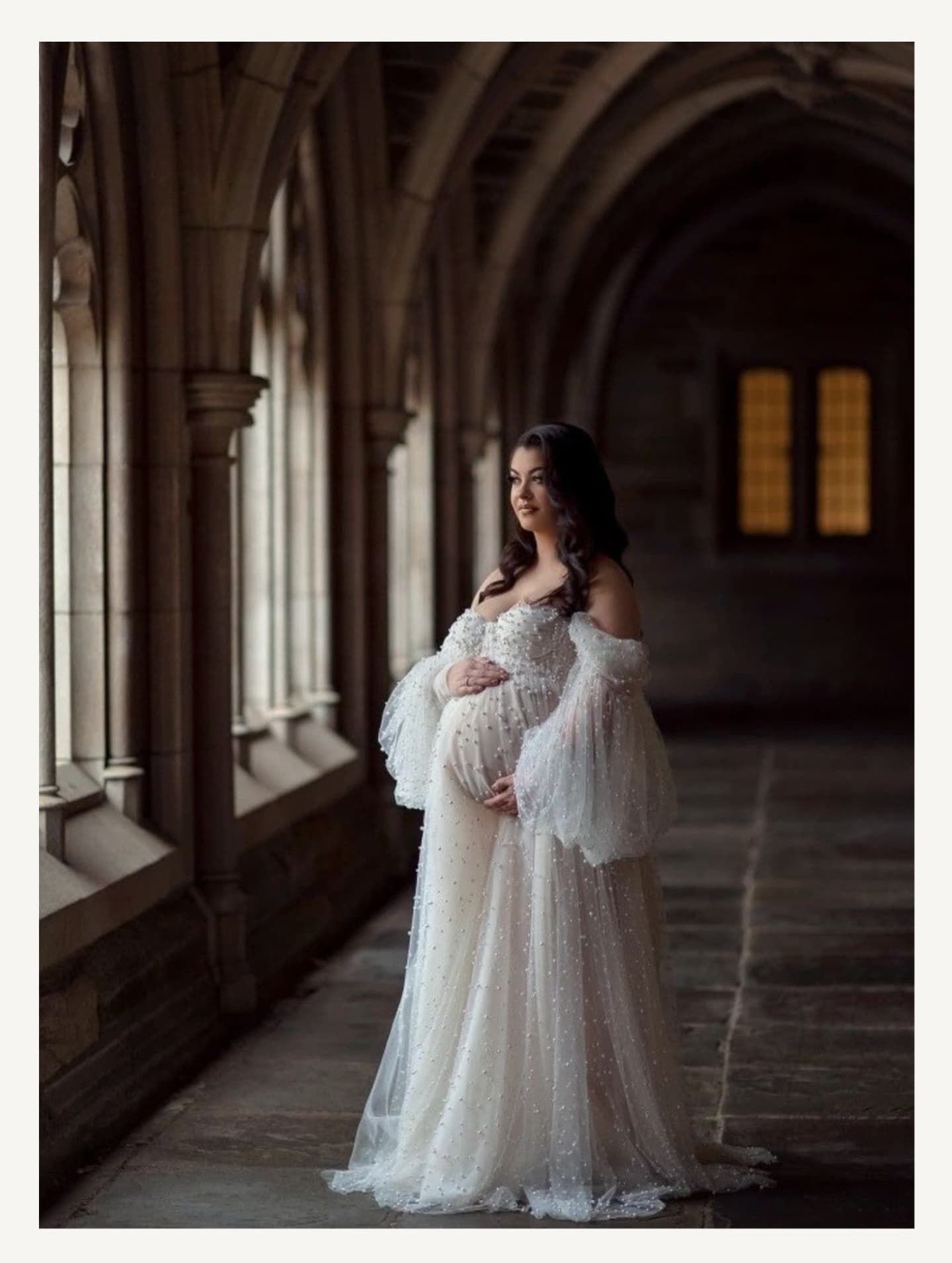 Romantic maternity portrait in cathedral hallway wearing vintage-inspired white lace dress.