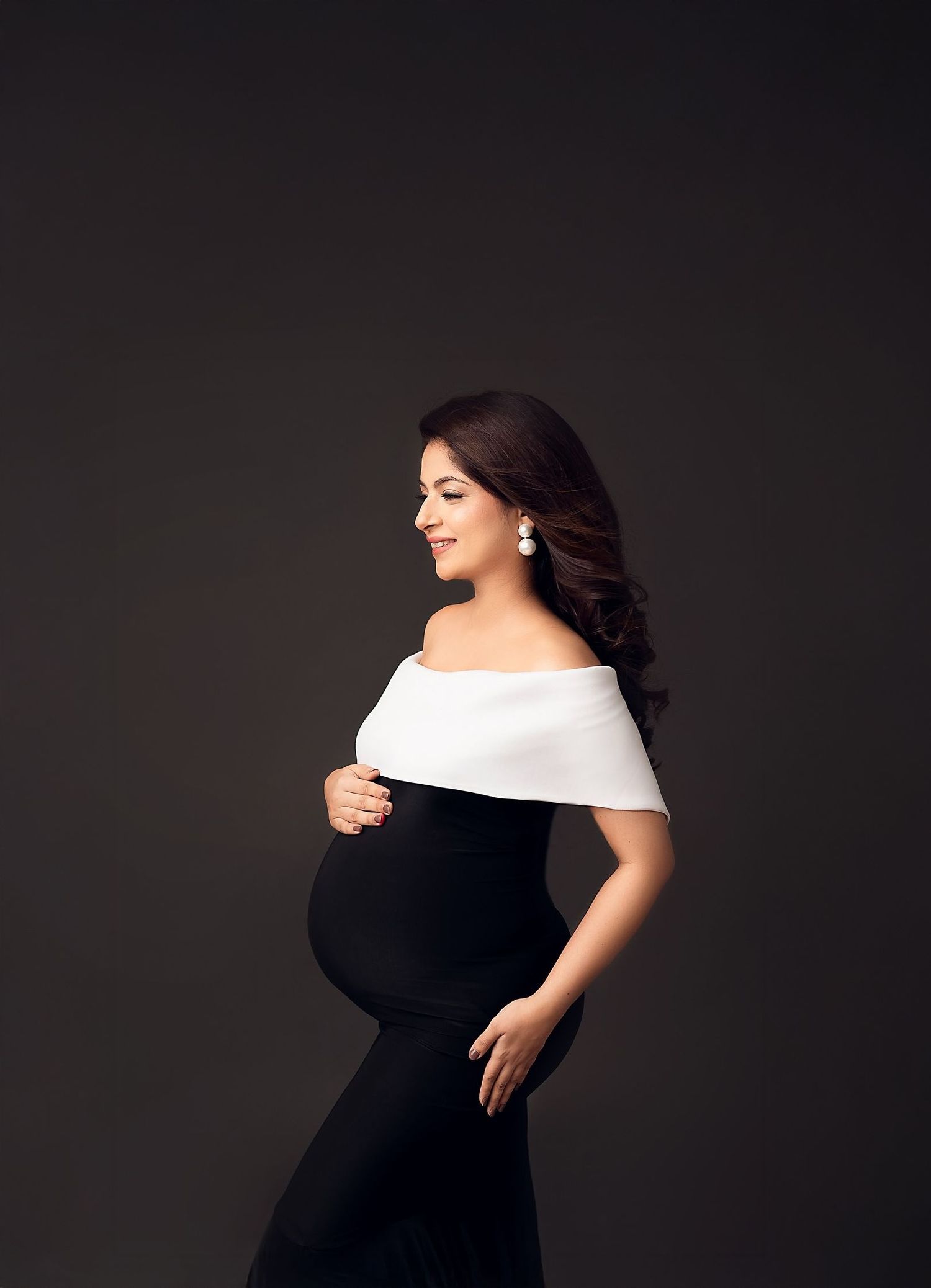 Elegant maternity portrait session featuring black dress and dramatic poses.