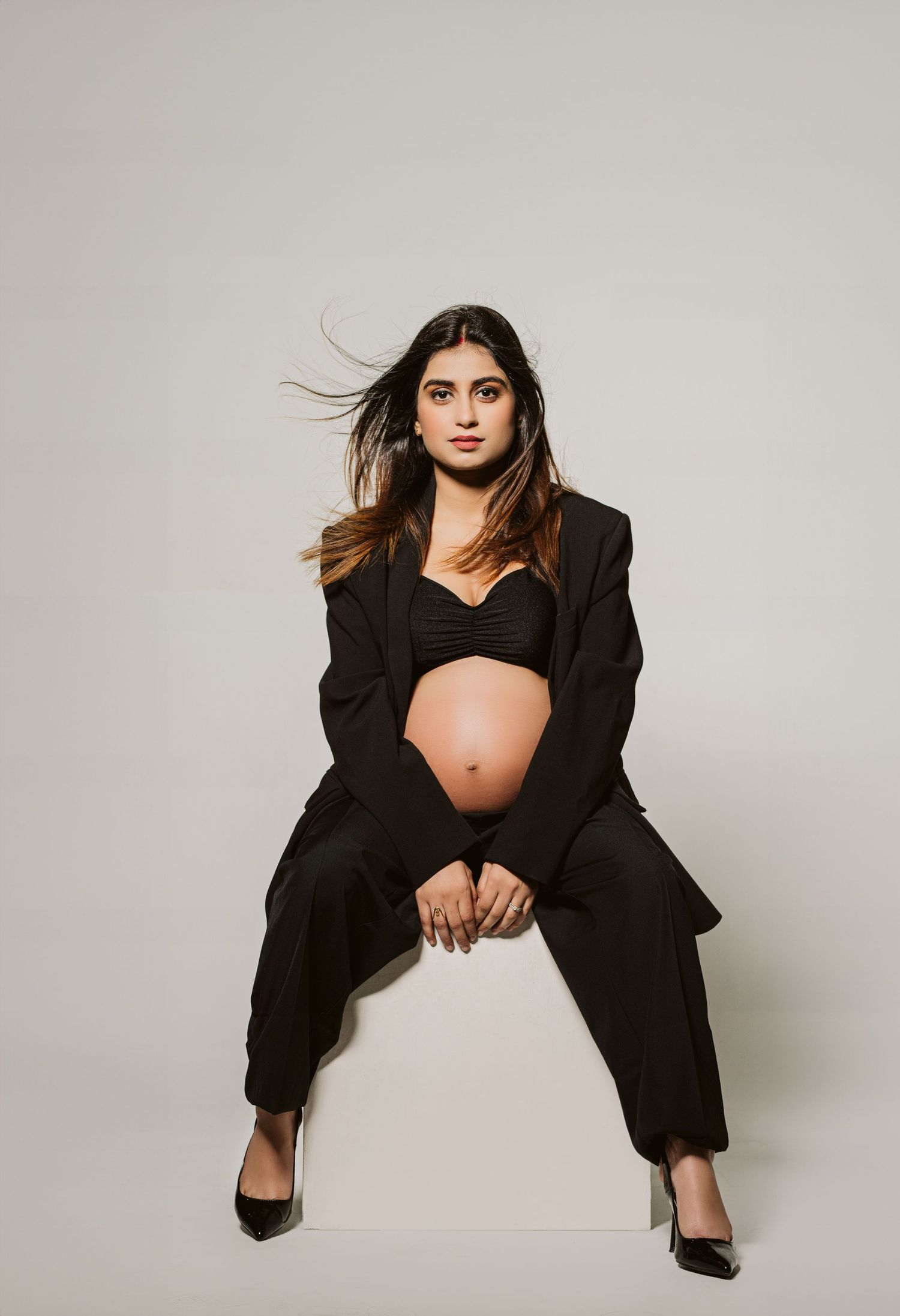 Fashion forward maternity portraits in black blazer showing artistic poses.