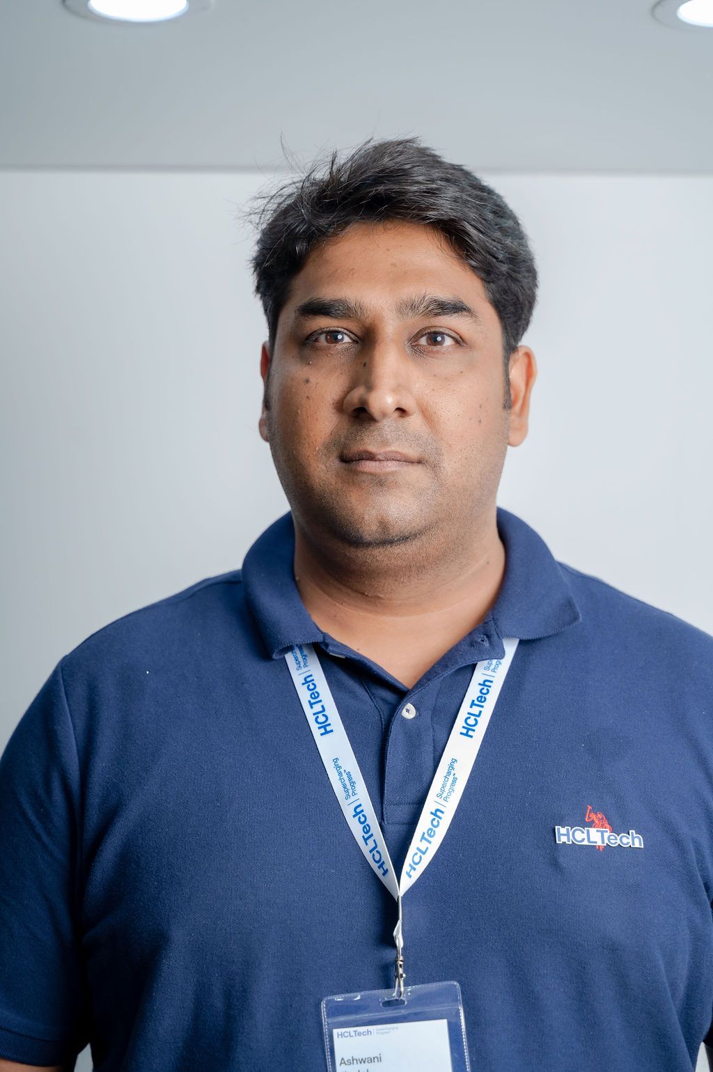 Multiple angles of person wearing navy polo shirt with company lanyard against light background.