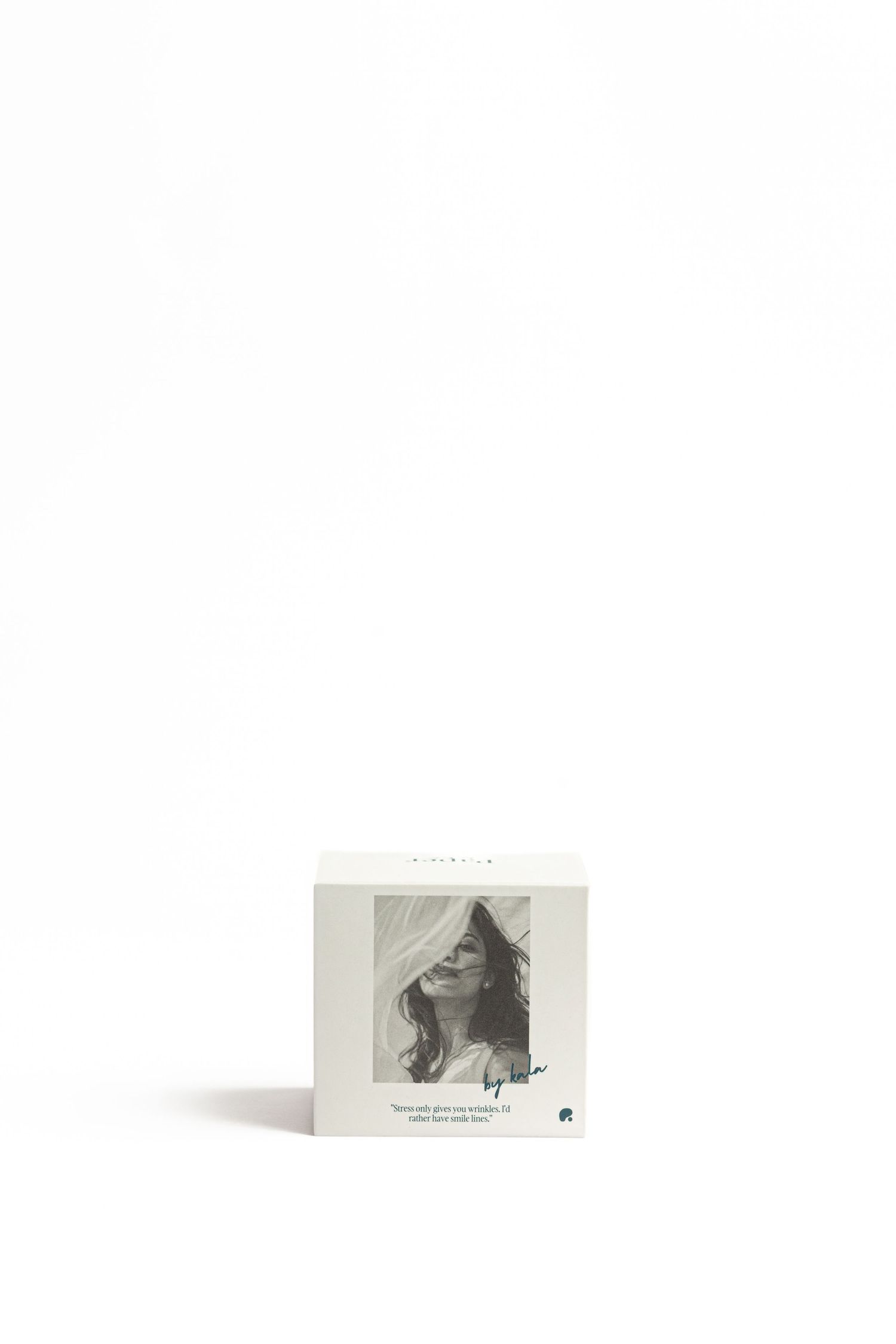 Small square white product box with a black-and-white portrait of a woman with long wavy hair and a green handwritten signature.