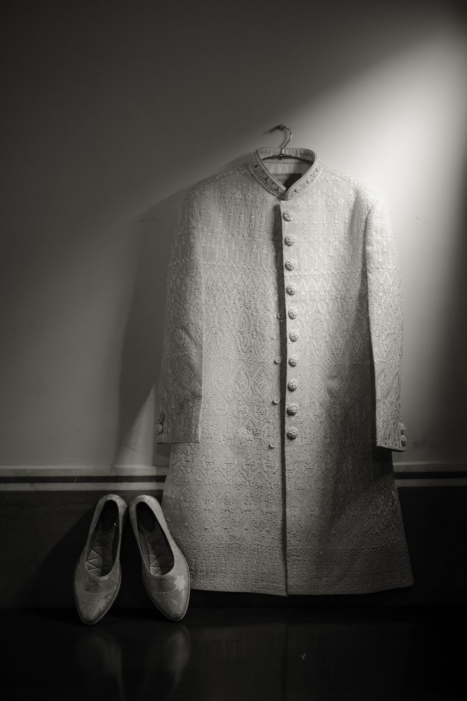 A series of black and white photographs showing a white garment with buttons and shoes in dramatic lighting.