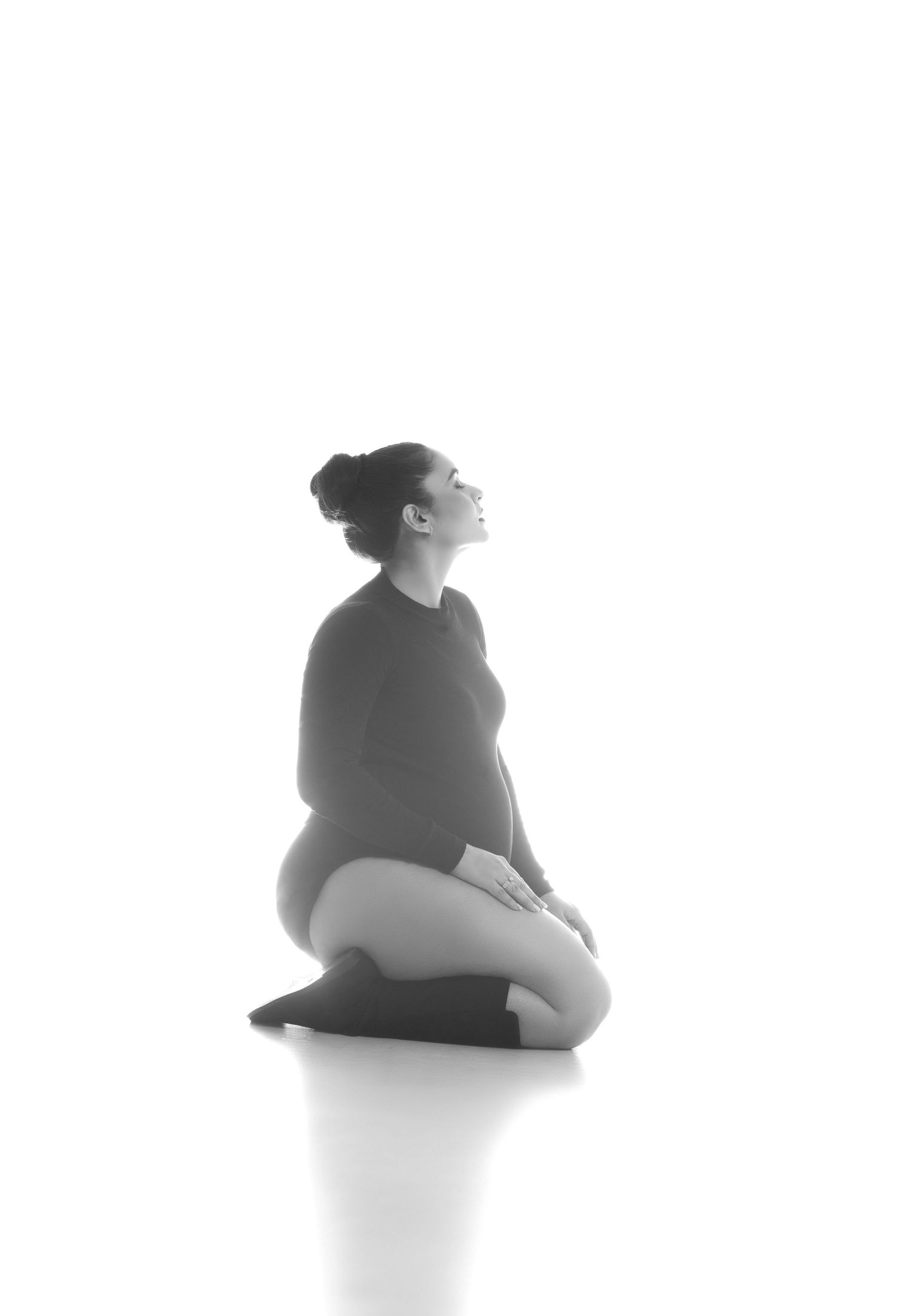 A black and white artistic series showing a figure in meditative seated poses against a minimalist white background.