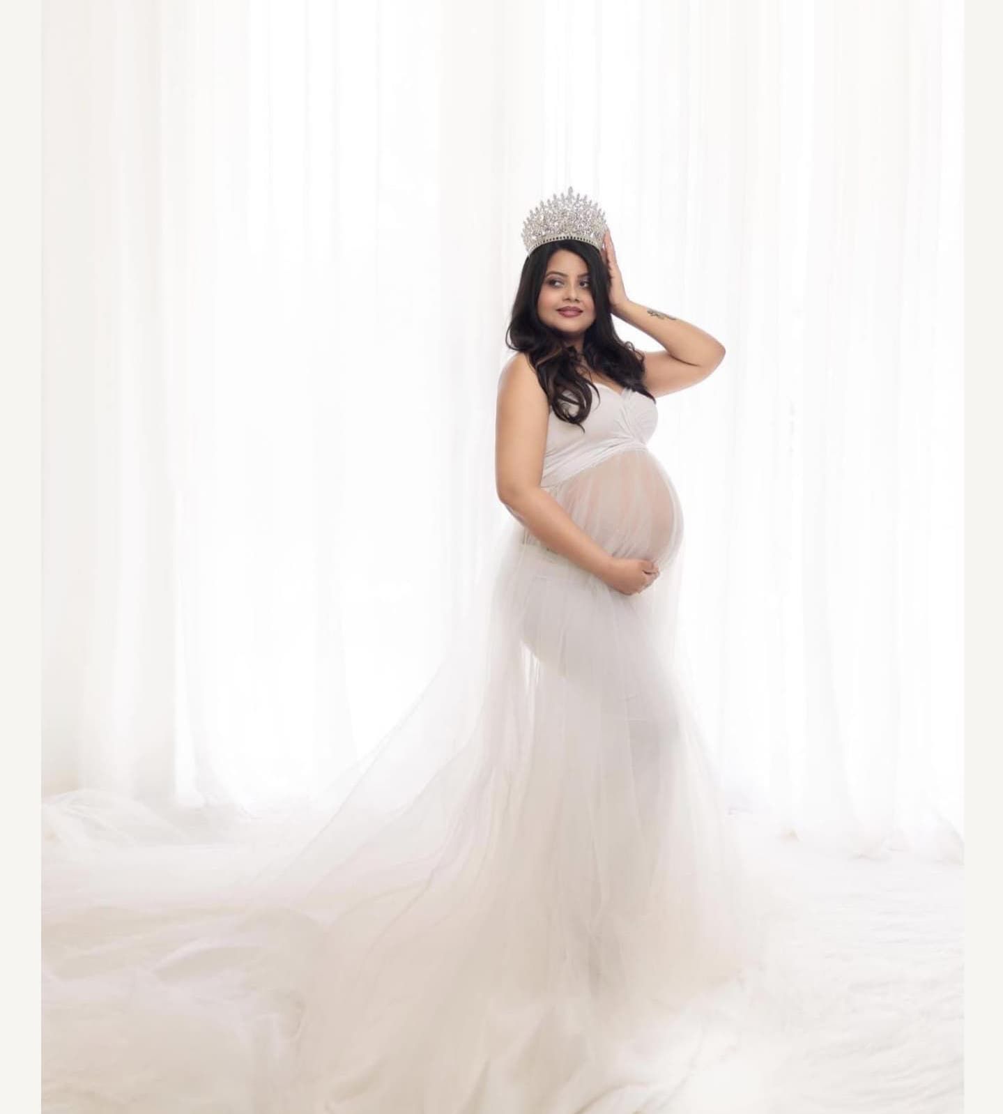 High-key maternity portrait series with flowing white fabric and soft lighting.