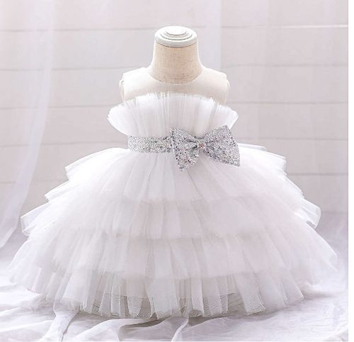White tulle baby dress with silver bow and tiered ruffles displayed on mannequin.