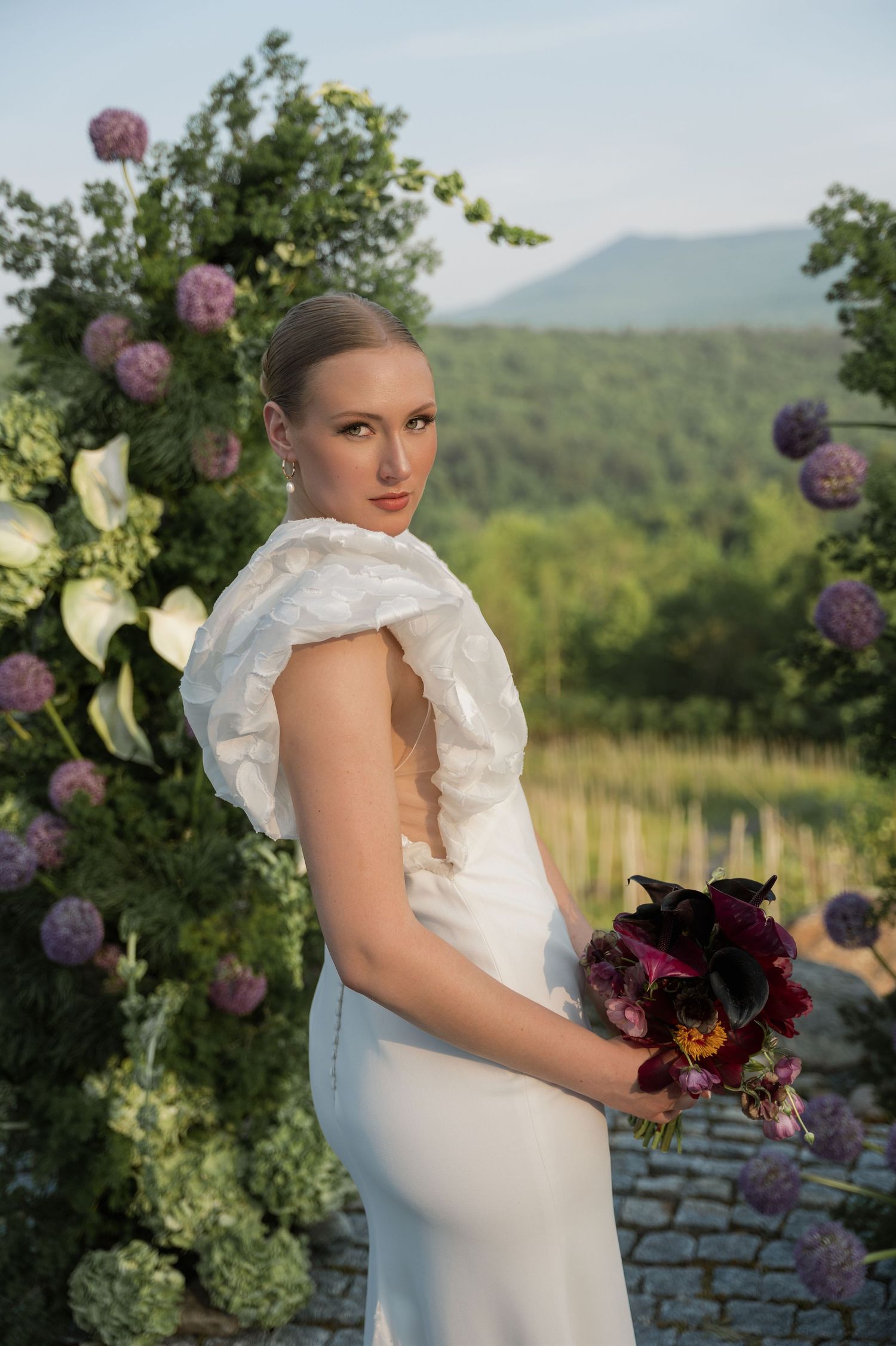 Four romantic outdoor bridal portraits featuring beautiful purple allium flowers and a white wedding gown against a mountain backdrop.