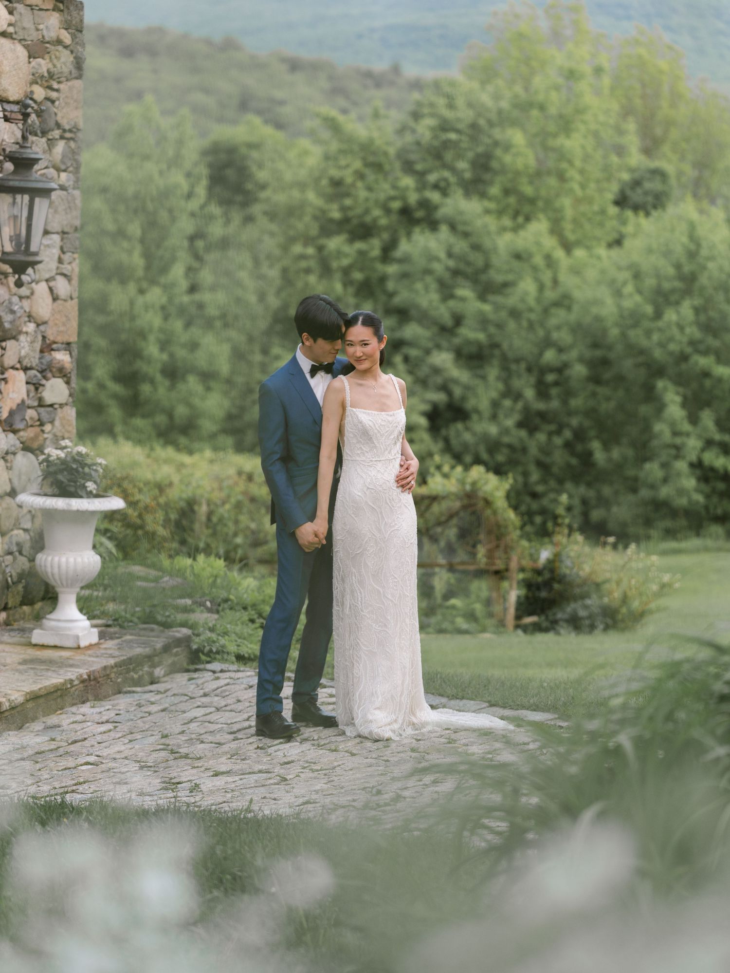 Romantic wedding portrait against stone architecture and mountain landscape.