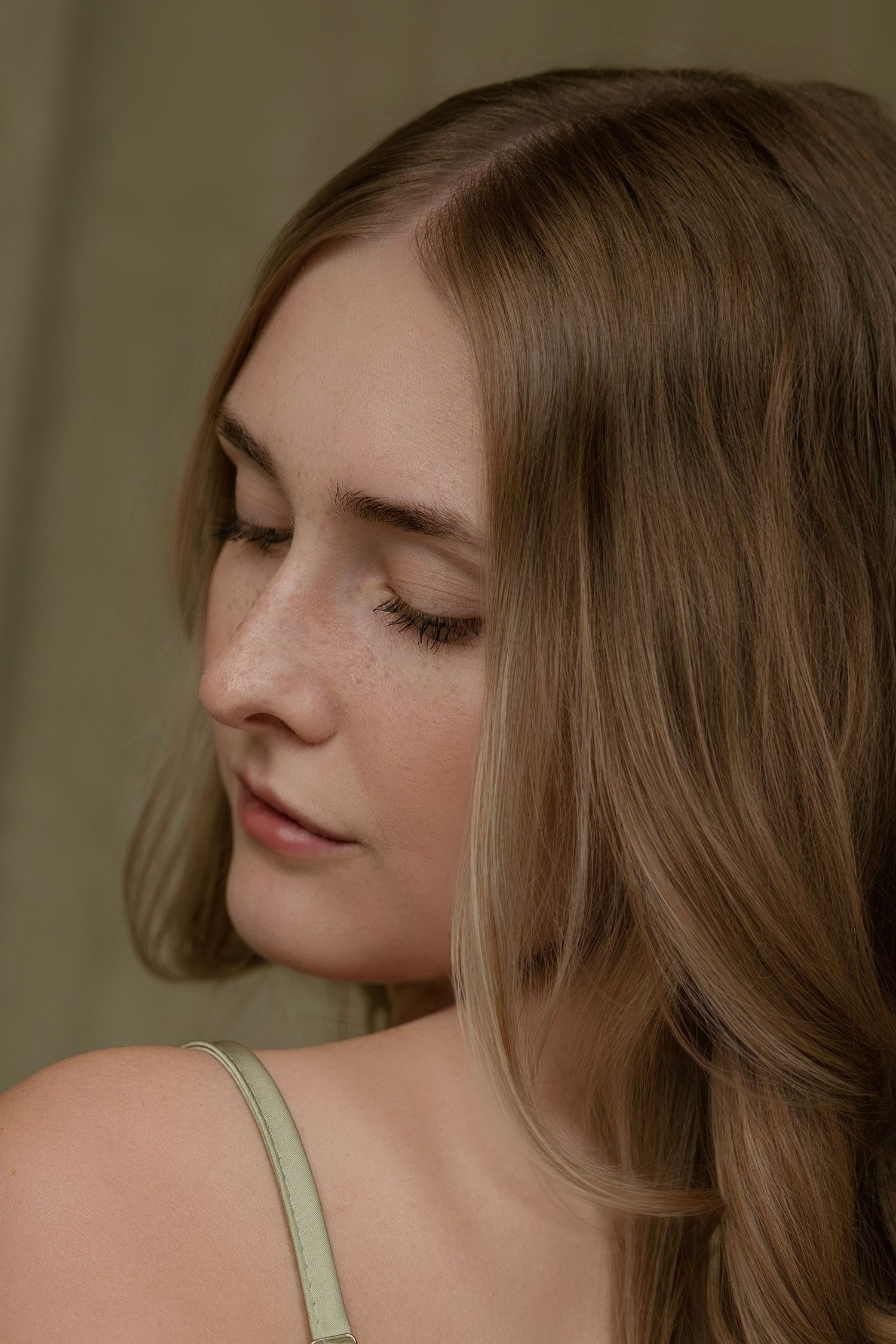 A series of profile views showing a person with long brown hair and freckles looking down with closed eyes.