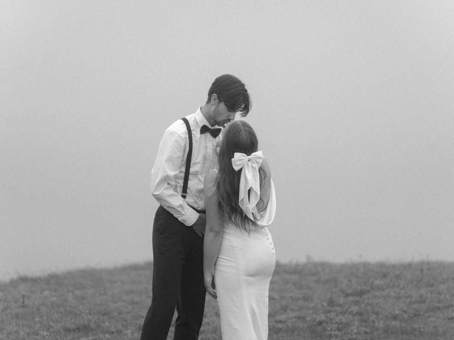 Black and white photo of a couple sharing an intimate moment in a natural setting.