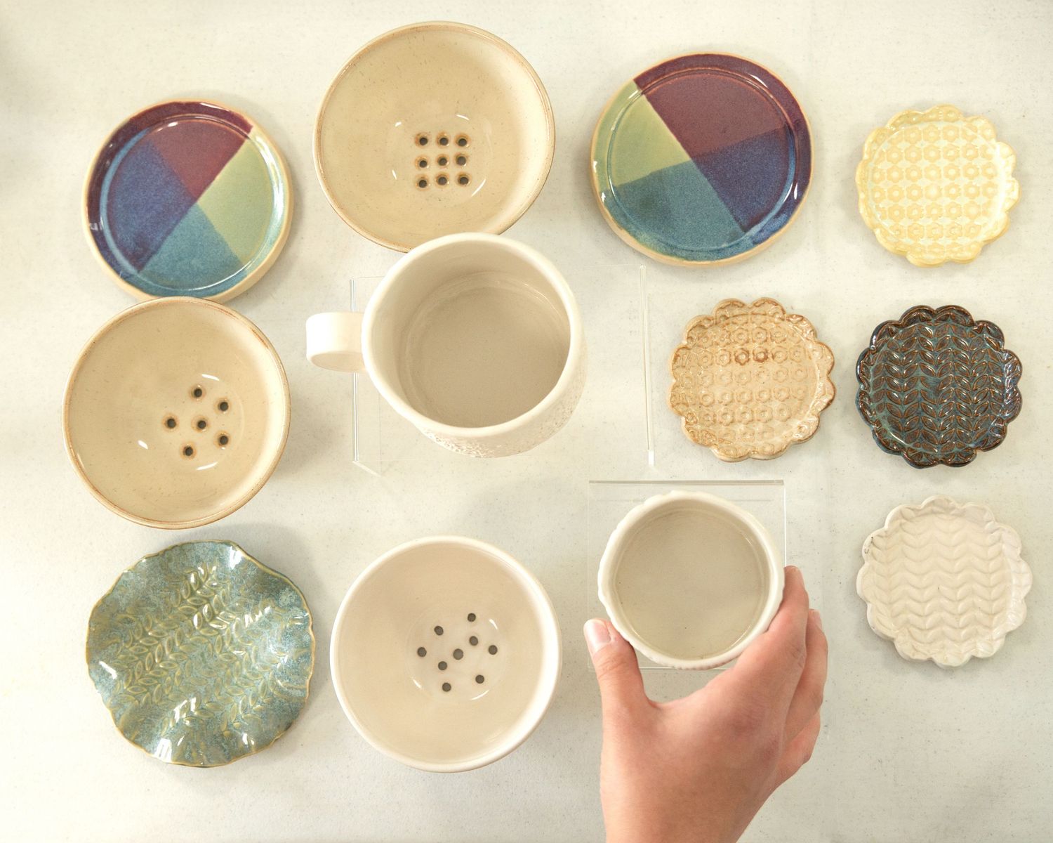 Artistic arrangement of handmade ceramic dishes and decorative plates in cream and blue tones.