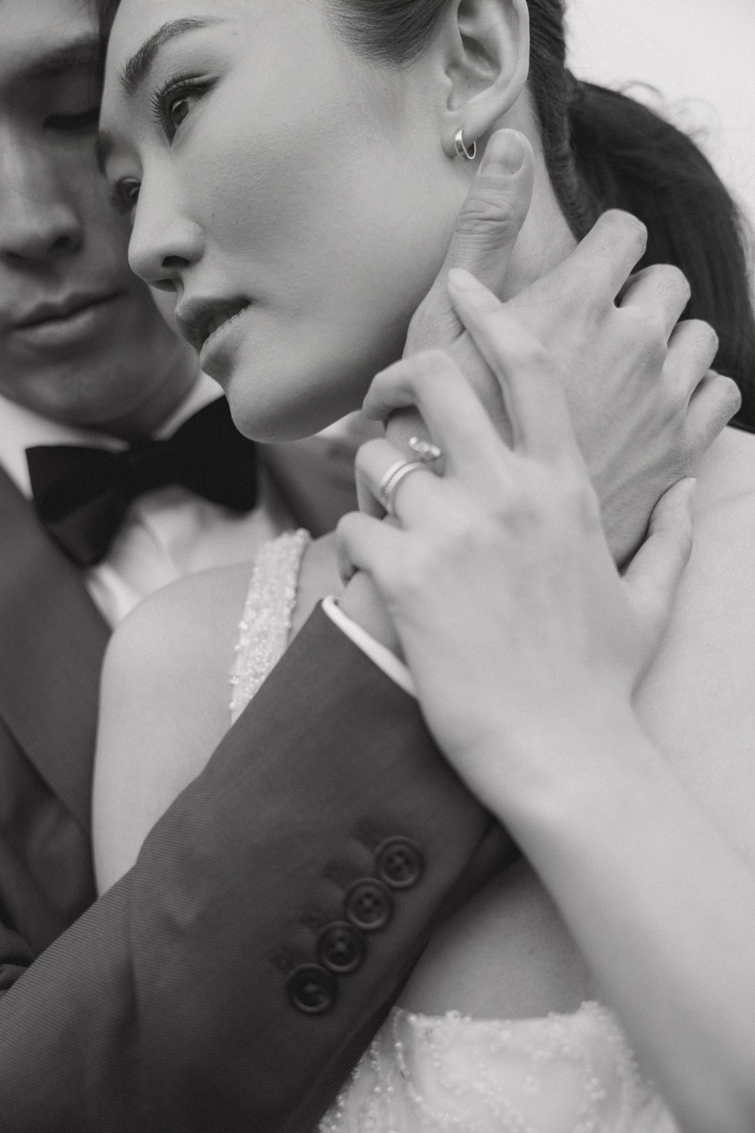 Intimate black and white portrait showcasing an elegant engagement ring and formal attire.