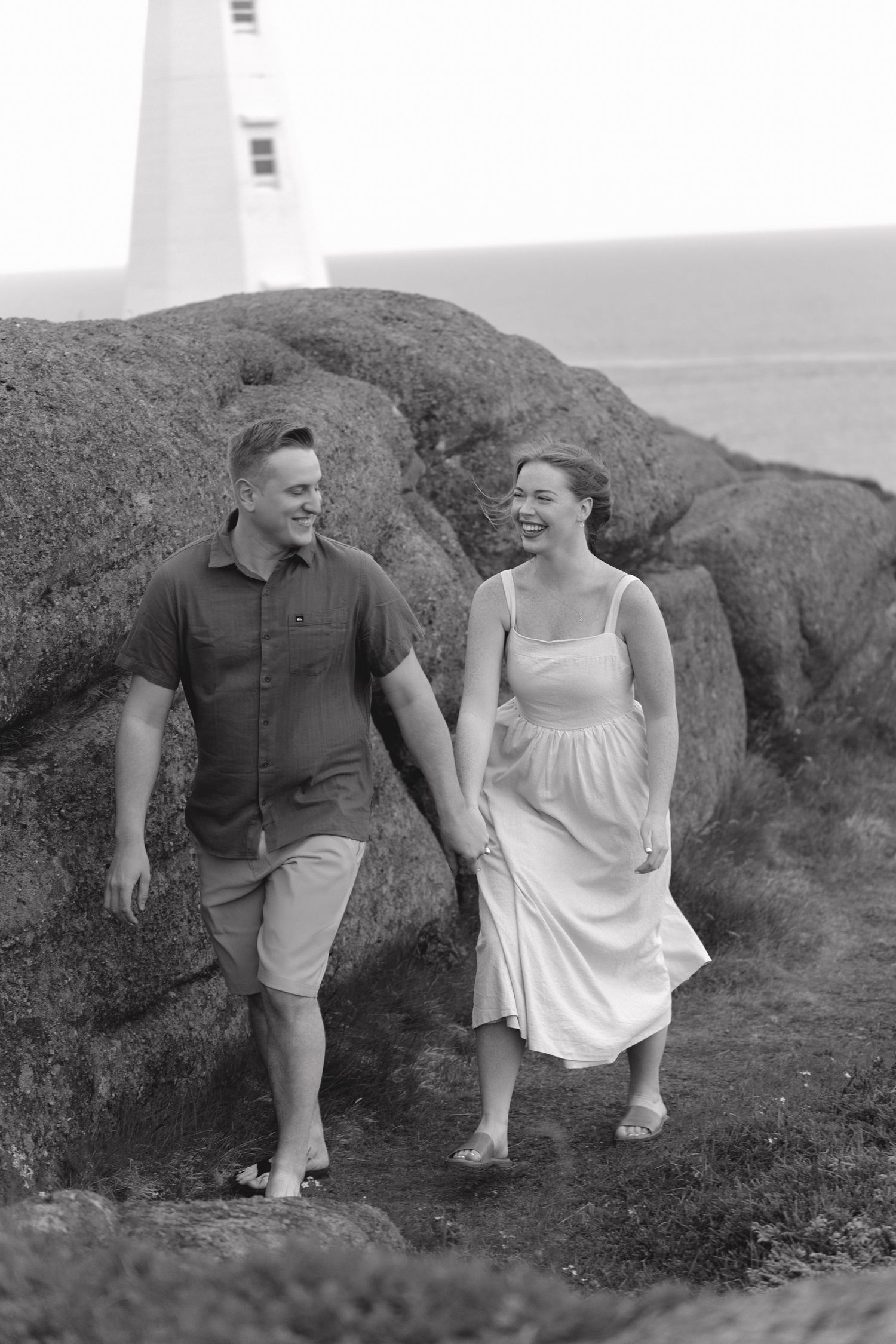 A couple sits on a hillside enjoying a playful moment together in black and white vintage photograph.
