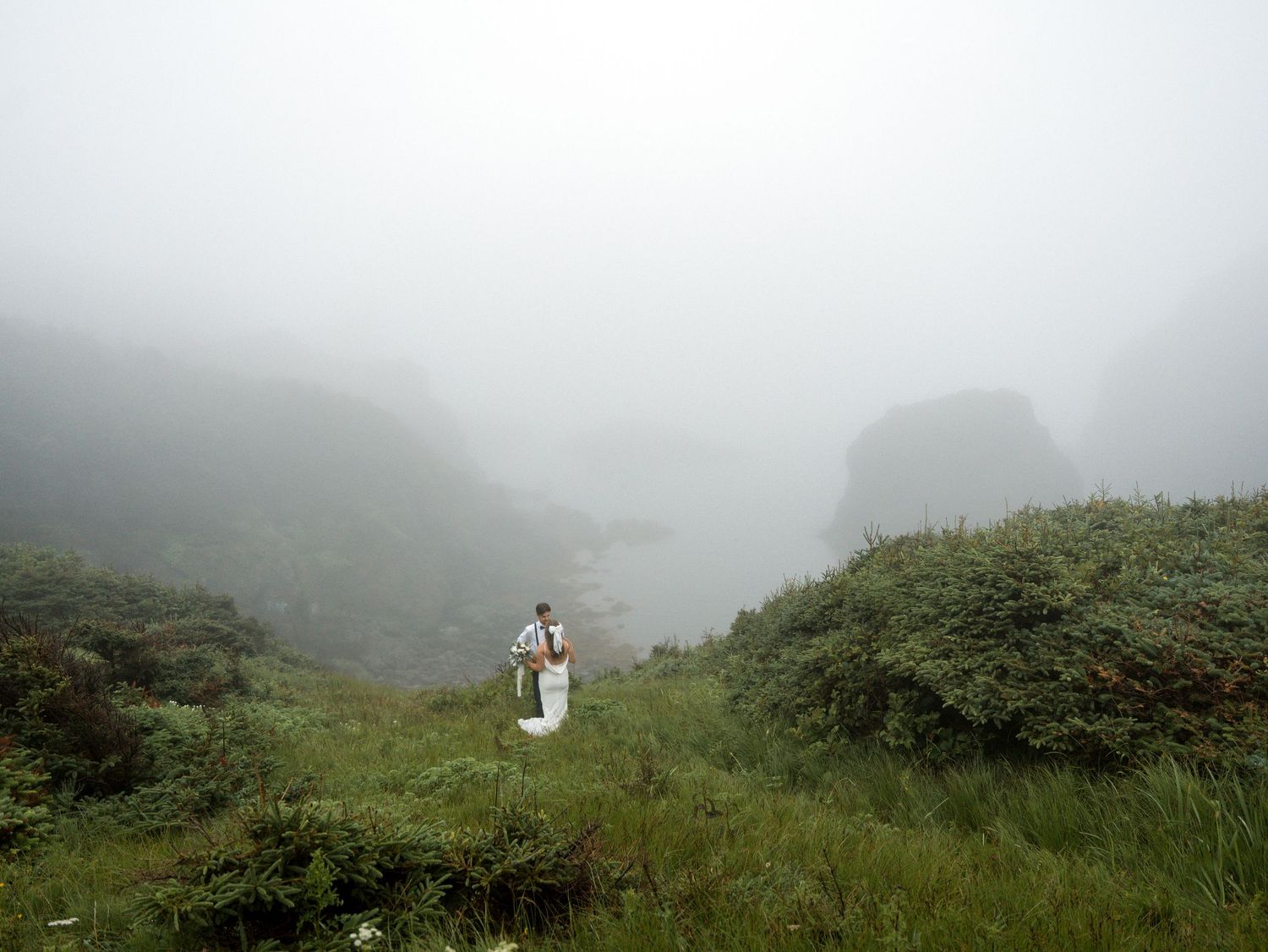 A misty mountain landscape view with green hills and foggy atmosphere.