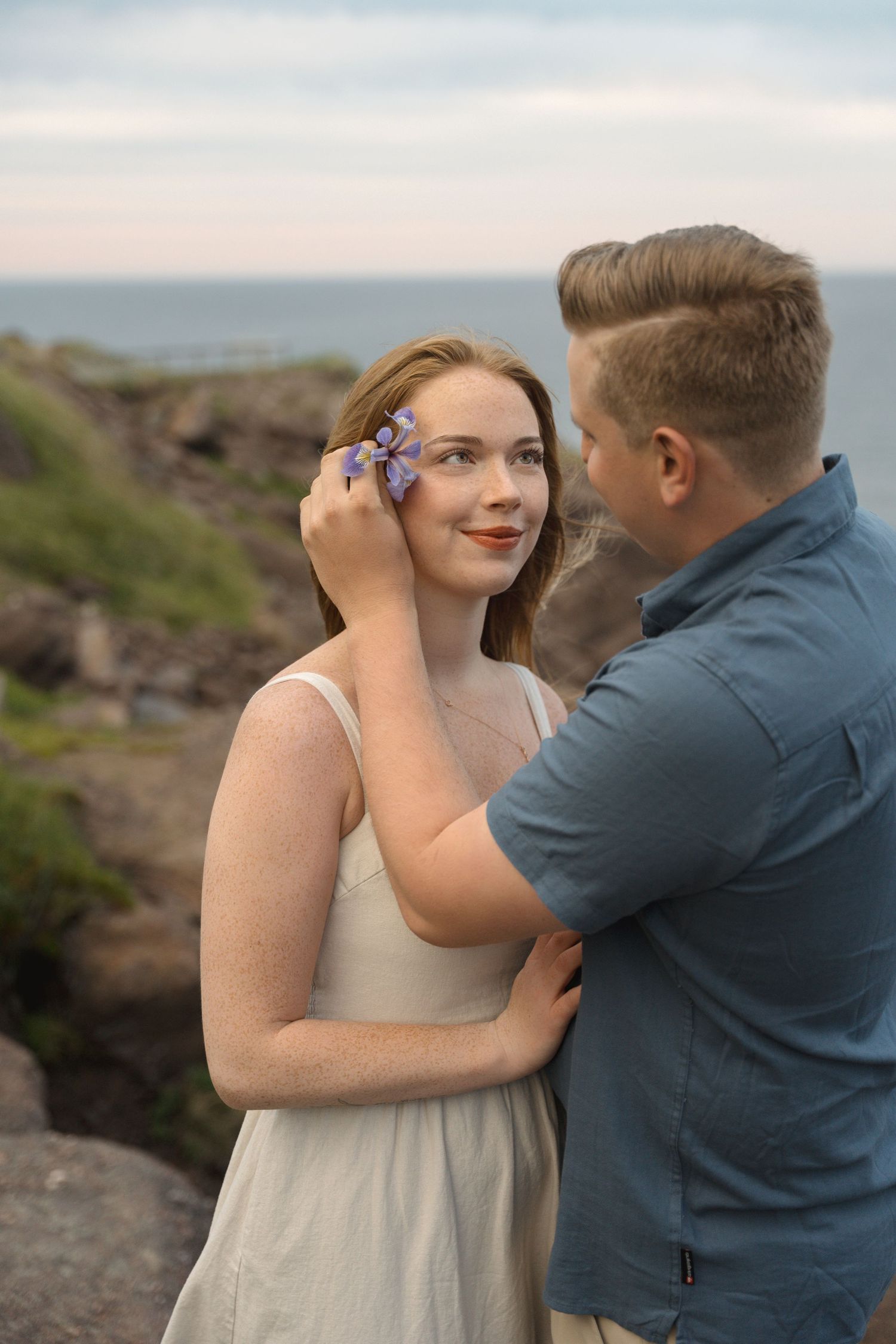 A couple shares an intimate moment against a rugged coastal backdrop during a romantic photoshoot session.