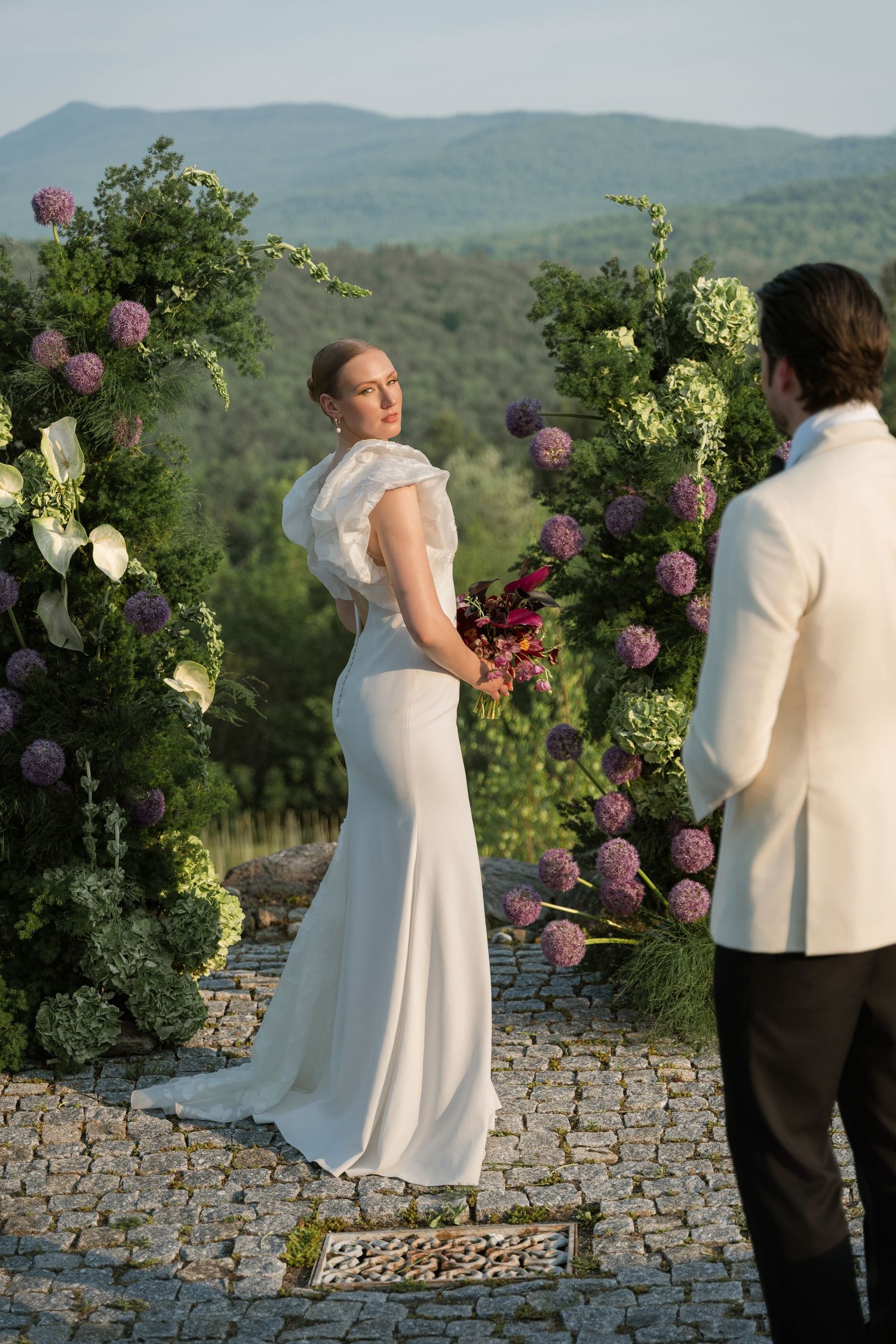 A couple shares a romantic moment at their mountain wedding ceremony surrounded by vibrant floral arrangements.