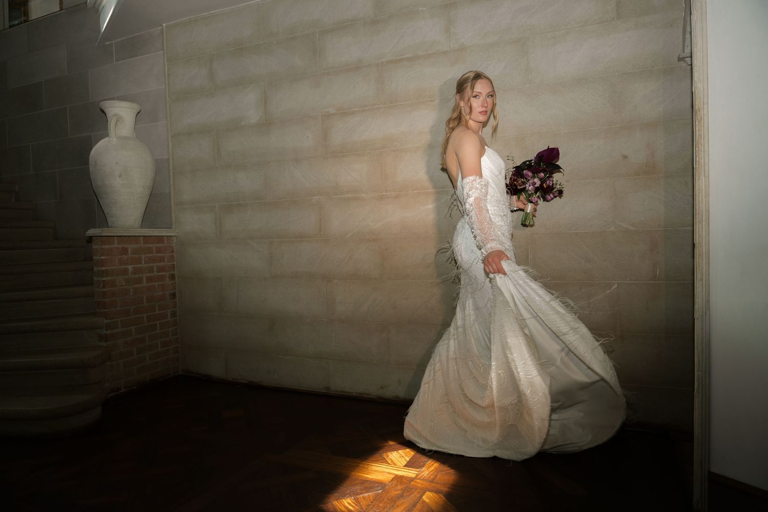 A flowing white wedding dress twirls gracefully in a dimly lit room with rustic wooden walls.