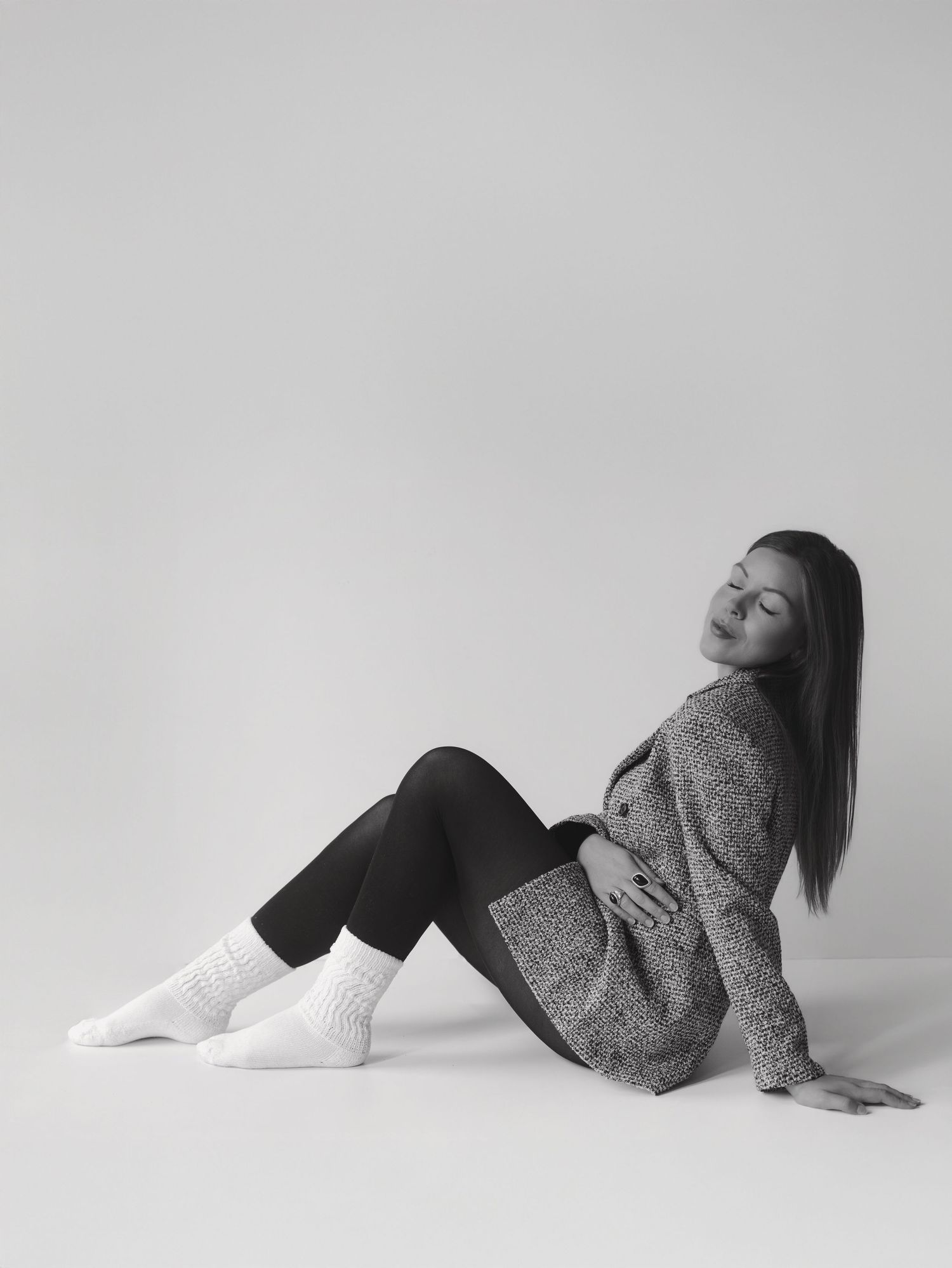 A series of black and white artistic portraits showing a person in a cozy sweater and leggings in various reclining poses.