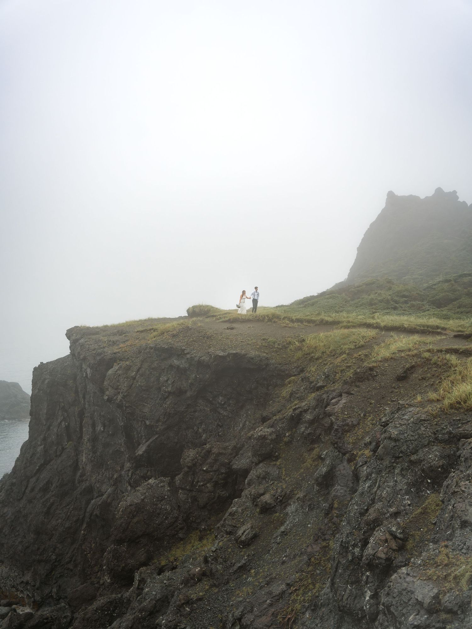 Foggy cliffs overlooking the ocean create a moody coastal landscape.