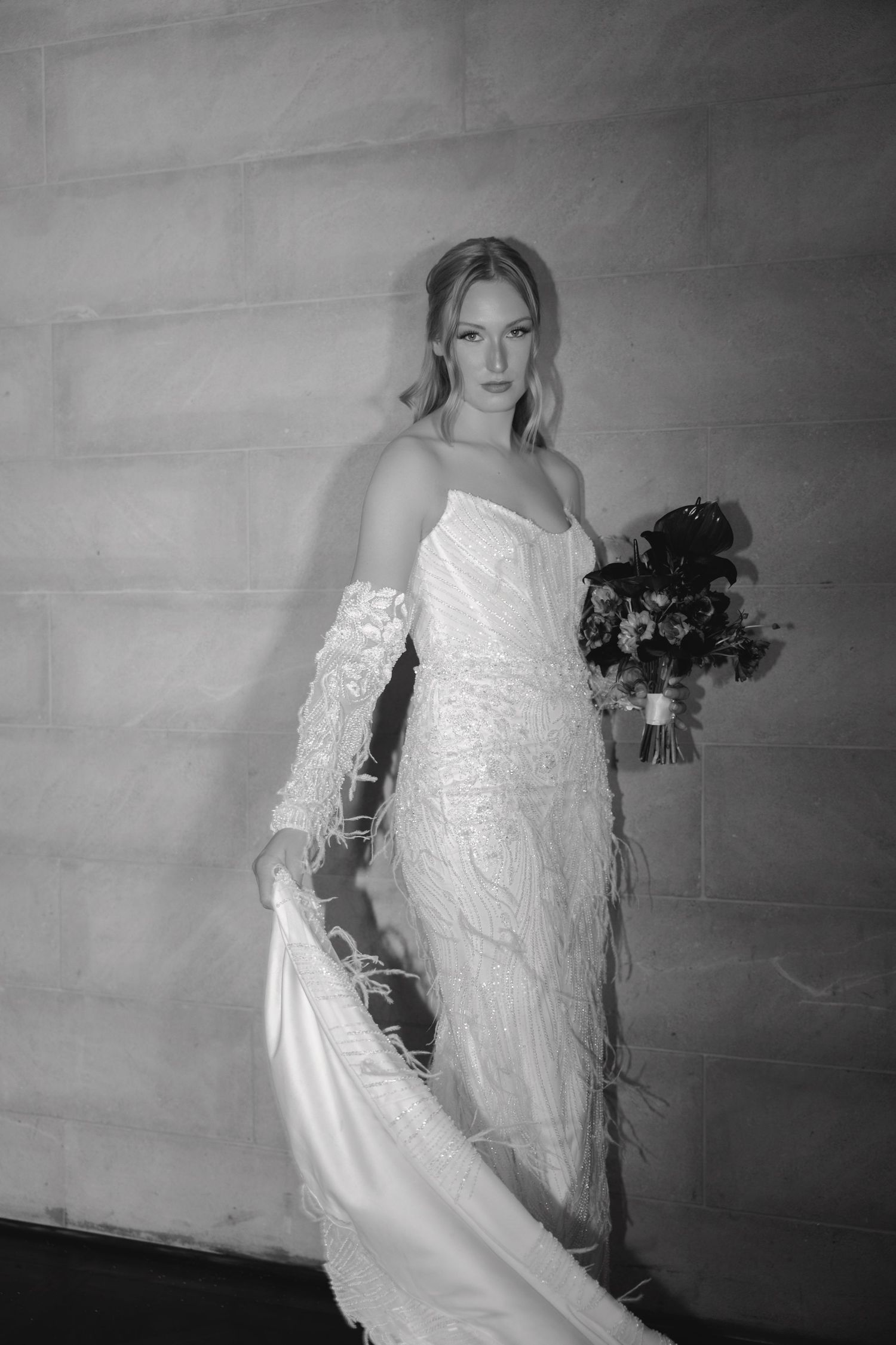 A series of black and white photos showing a person in a white lace wedding dress holding a dark bouquet against a plain wall.