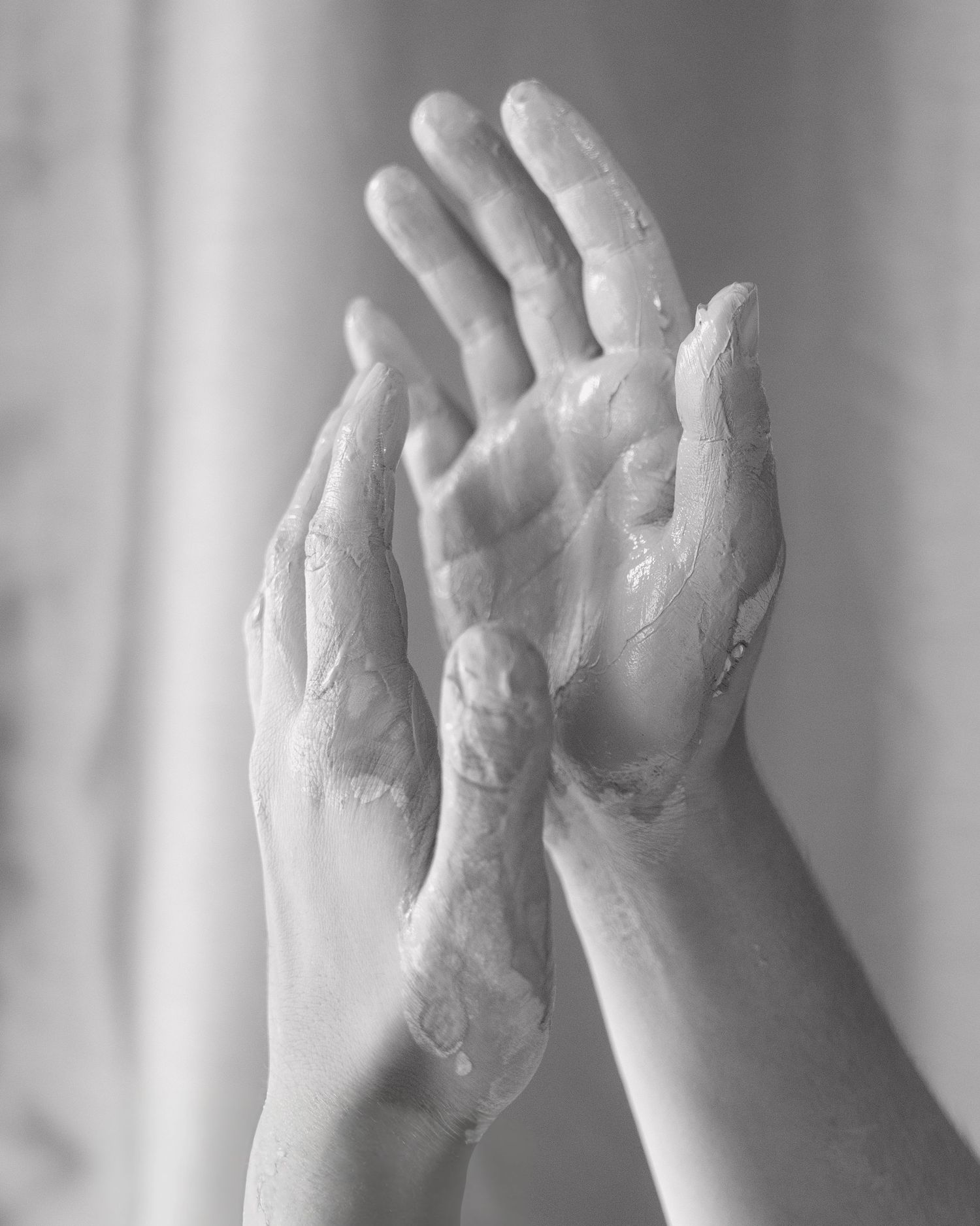 Black and white image of soapy hands washing under water.