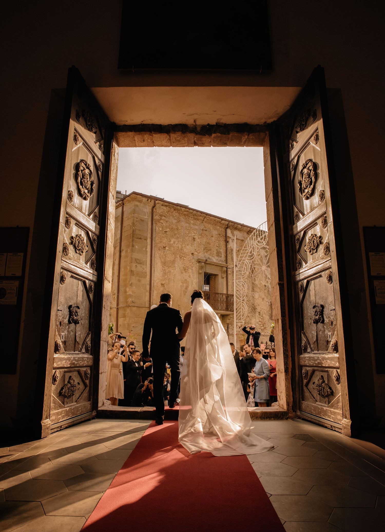 A dramatic church wedding sequence showing silhouettes against a bright doorway with flowing veil and red carpet.