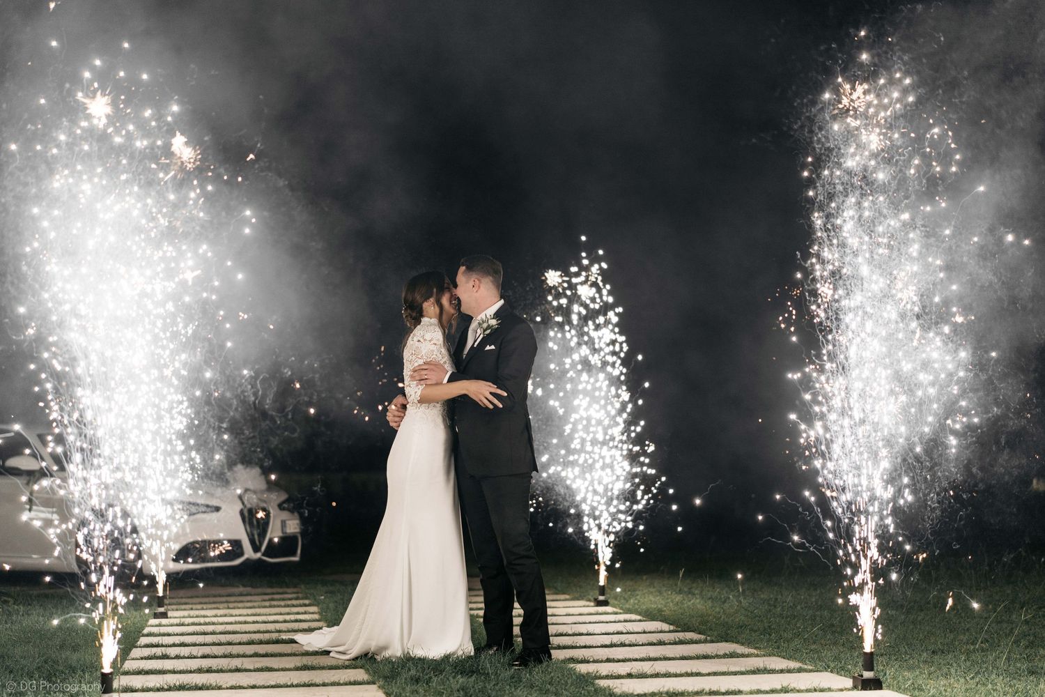 Nighttime wedding celebration with dramatic sparkler fountains creating magical light effects.