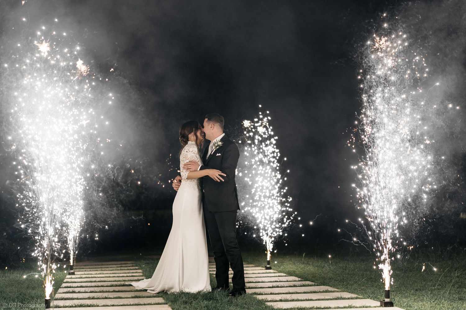 A wedding couple shares a romantic moment surrounded by sparkling cold spark fountains on their special night.