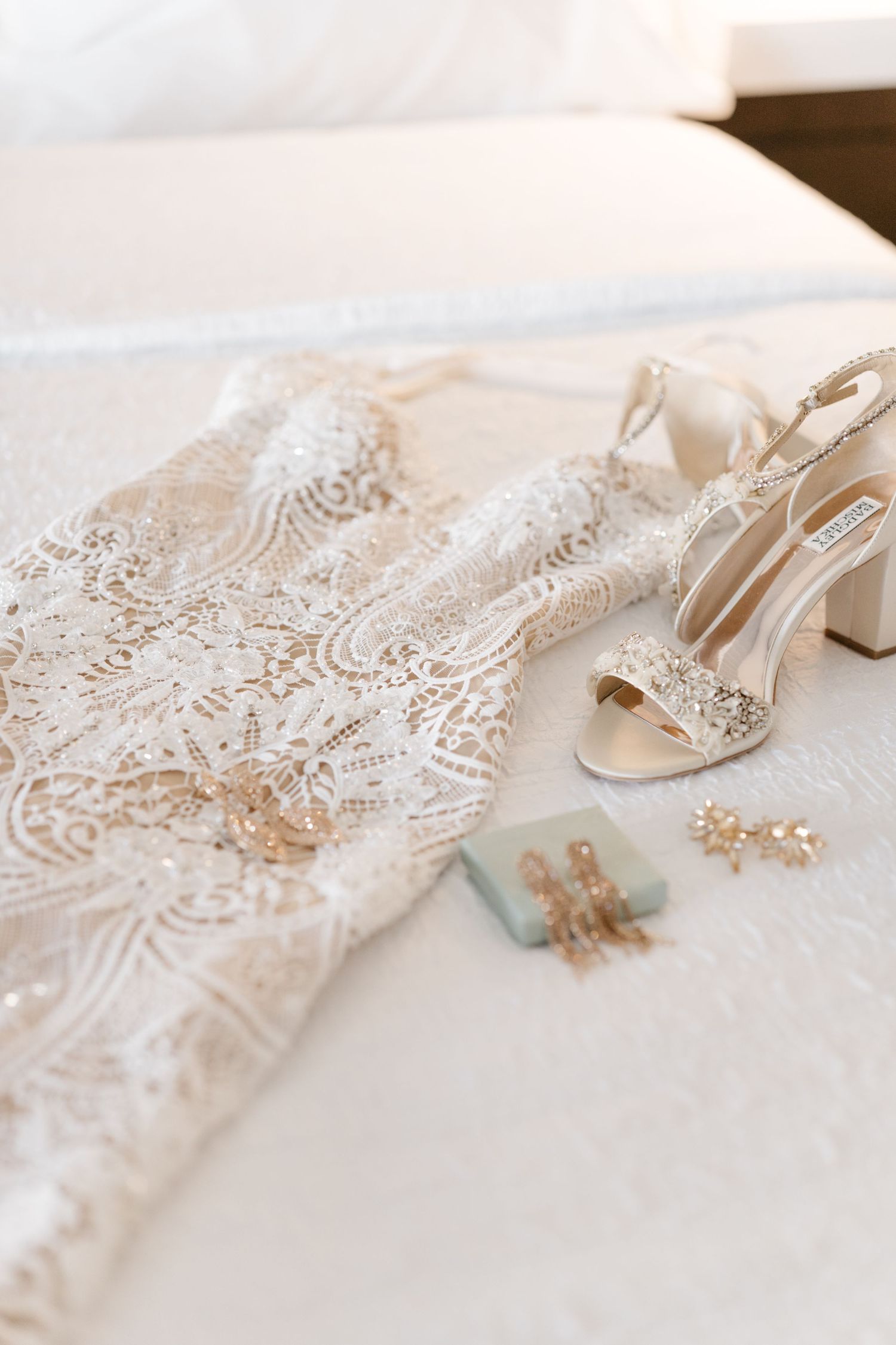 Delicate lace wedding dress detail with bridal accessories on white background.
