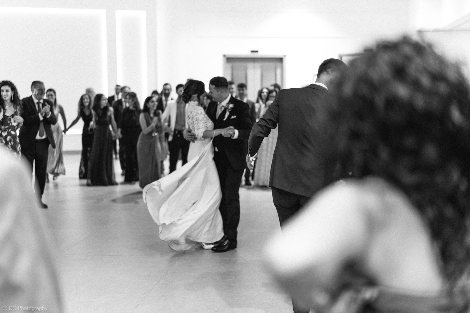 A bride and groom share their first dance surrounded by guests at an elegant wedding reception.