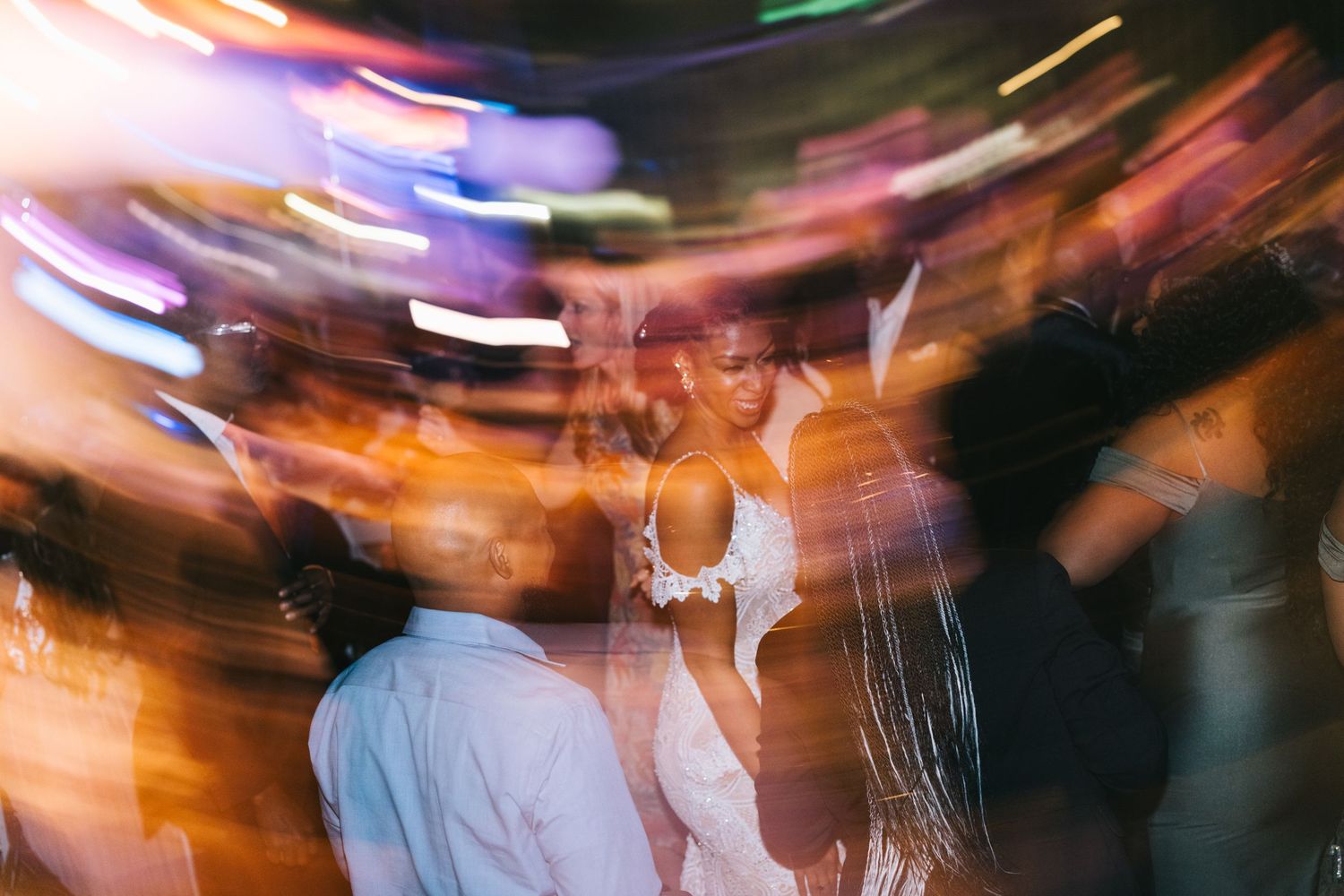 Blurred motion shot of a dance floor with colorful lights creating streaks of orange and purple.