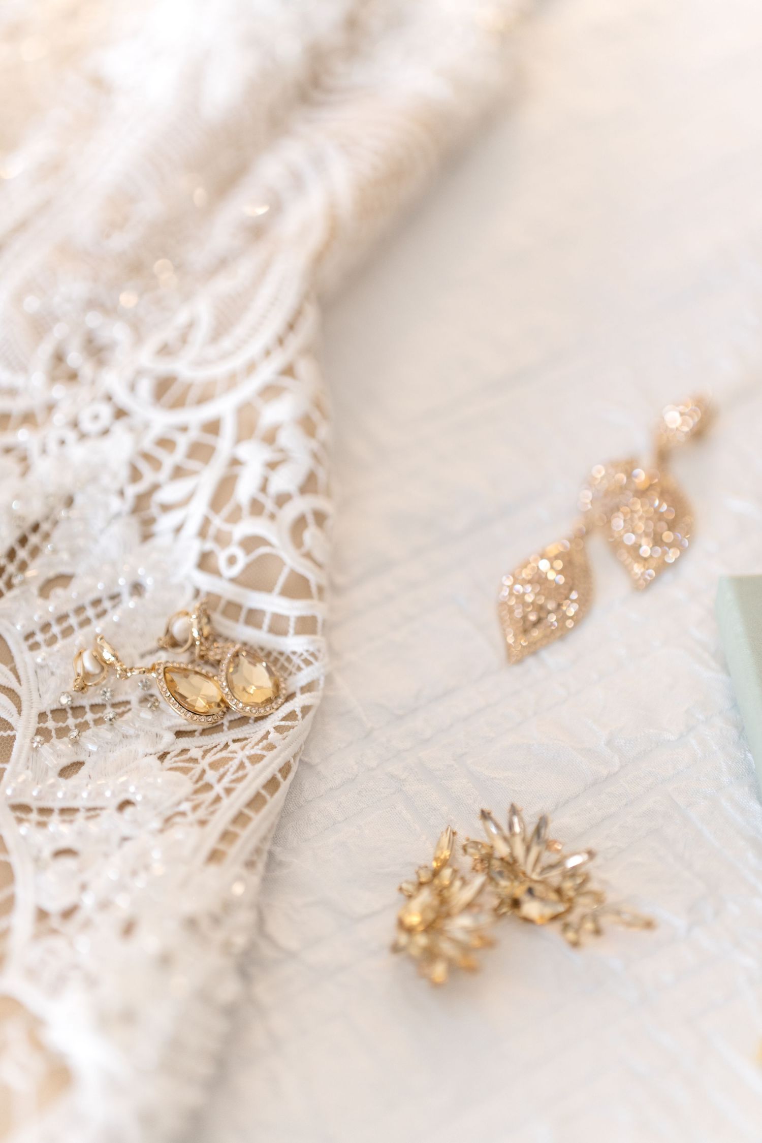 Intricate gold jewelry details on white lace wedding fabric.