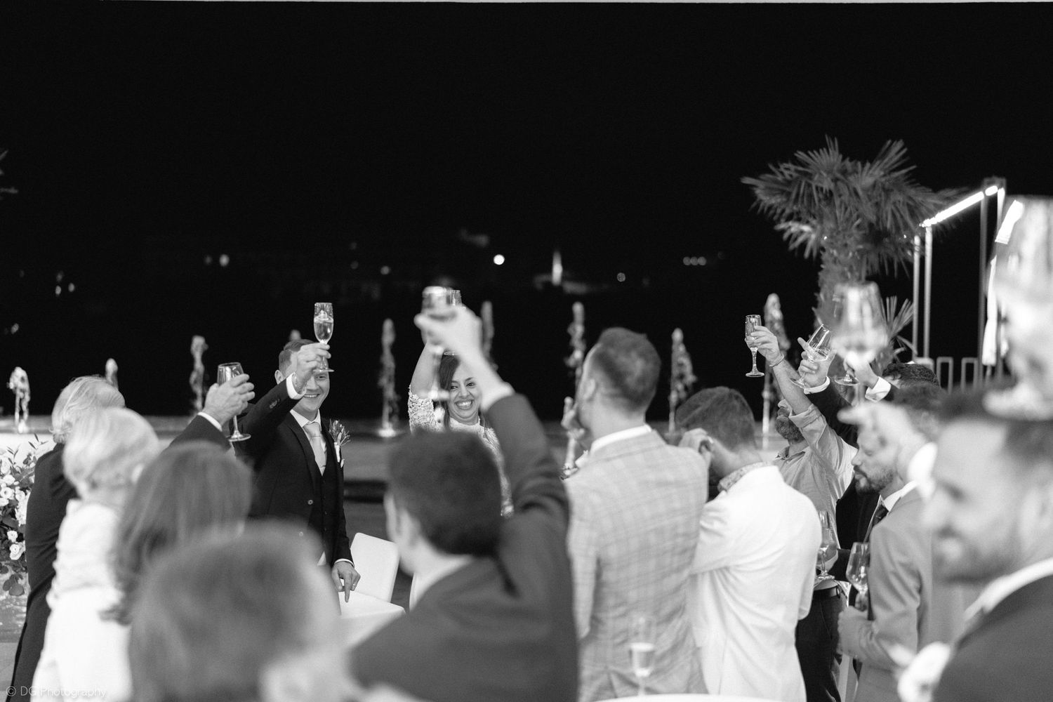 A black and white panoramic photograph shows a crowd gathered at an outdoor event with palm trees in the background.