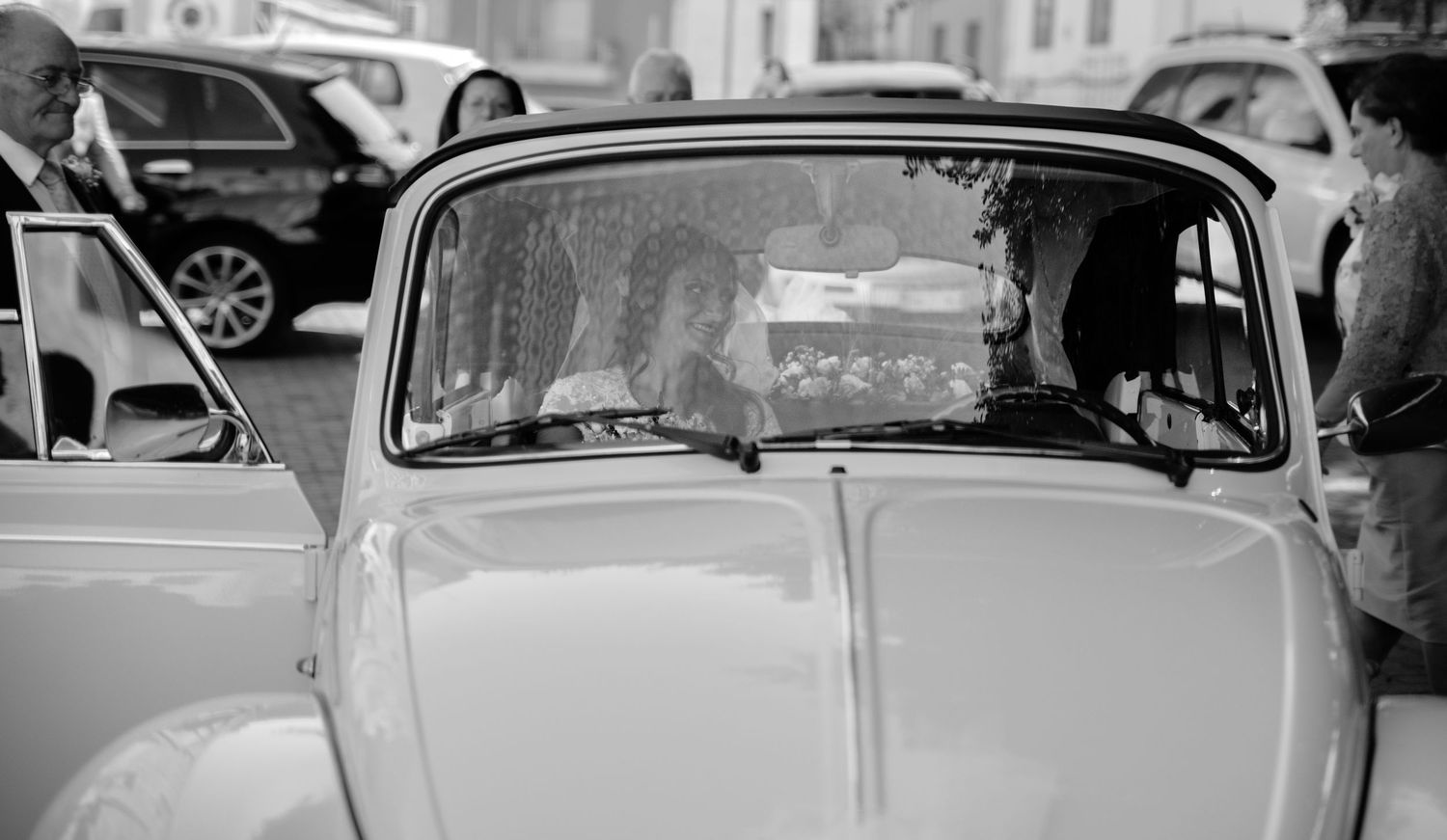 Vintage black and white photograph showing a line of classic cars parked on a city street.