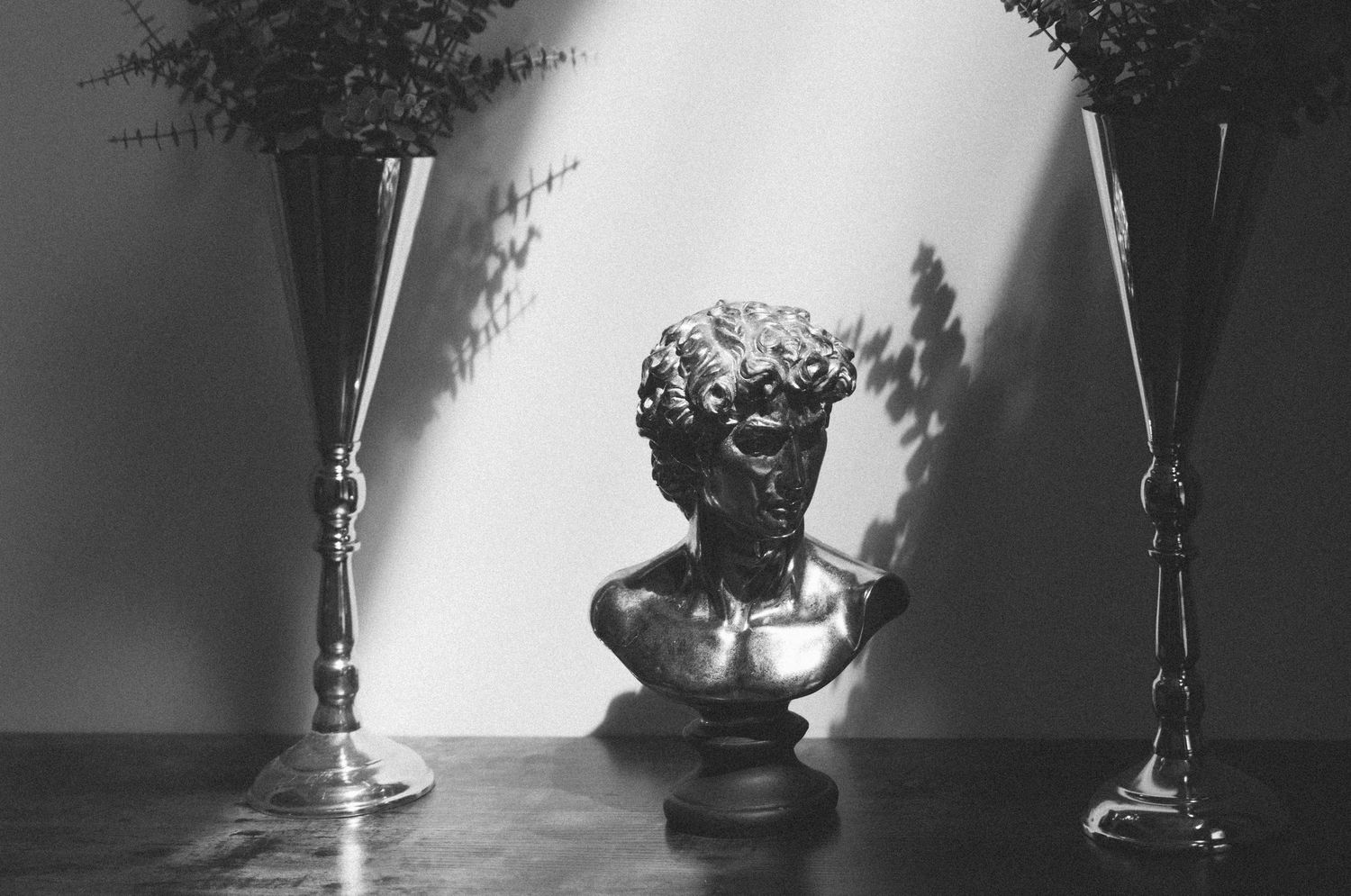 Dramatic black and white still life with decorative busts and candles.